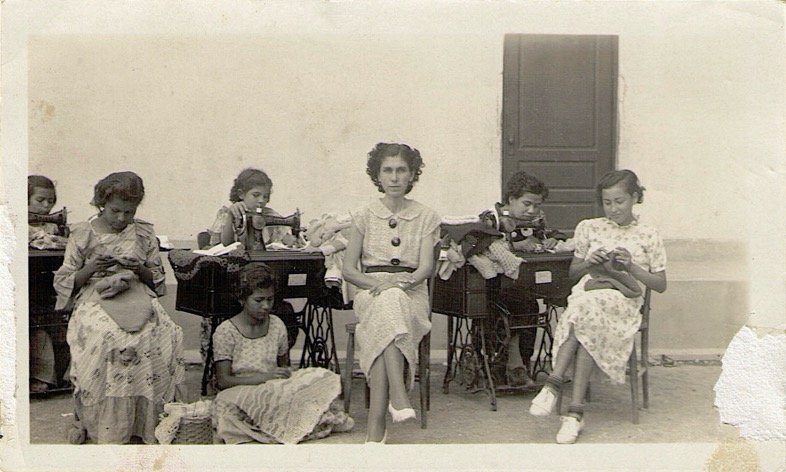 Lola sewing. She is on the far right, wearing socks. Photo courtesy of María A. De la Cruz