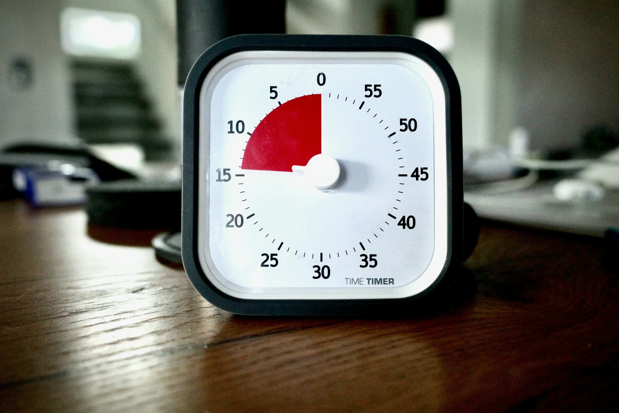 A black and white time timer on a wooden table showing 14 minutes.