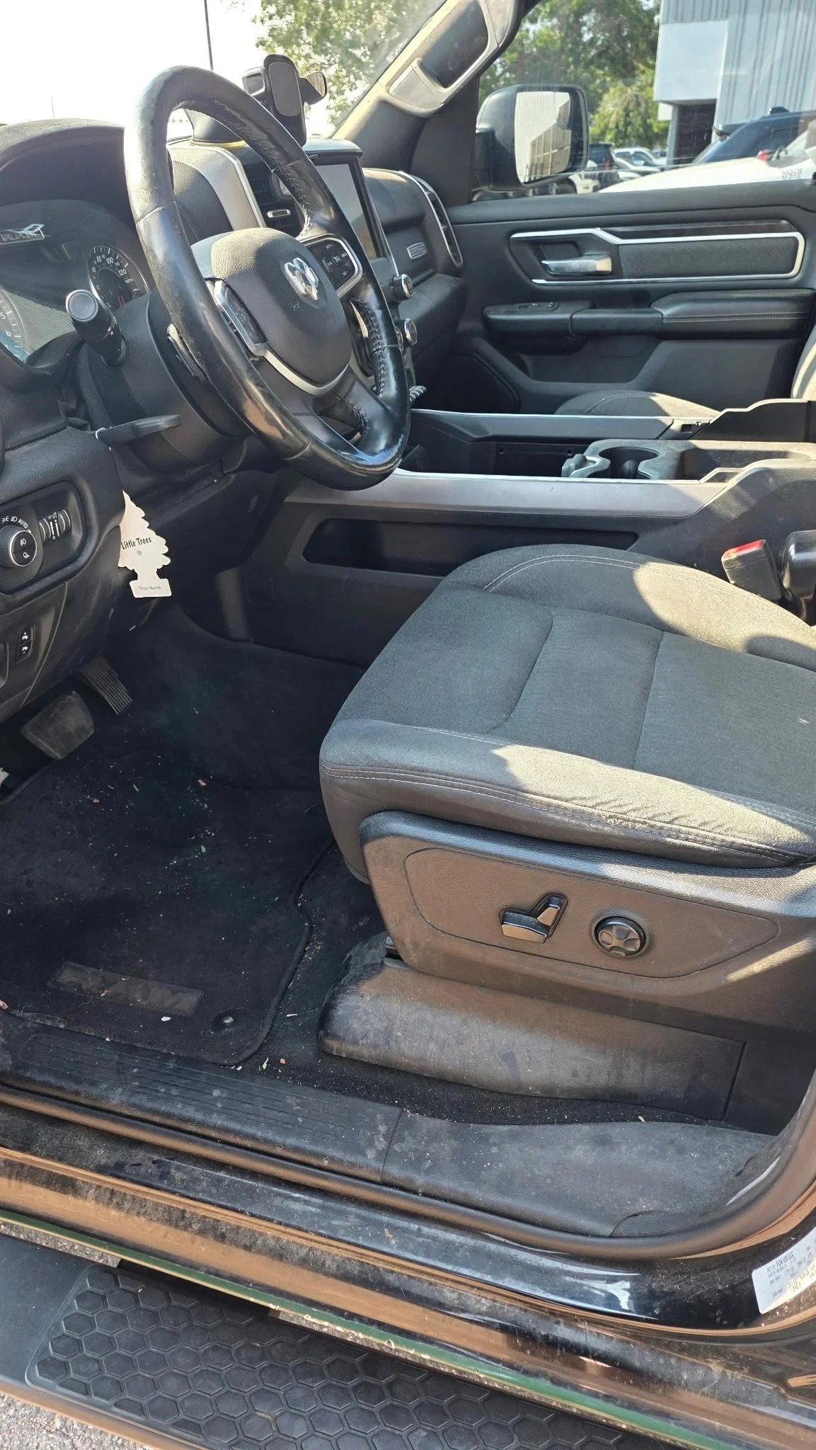 Interior of a black pickup truck showing the driver's seat, steering wheel, dashboard, center console, and the front passenger seat.