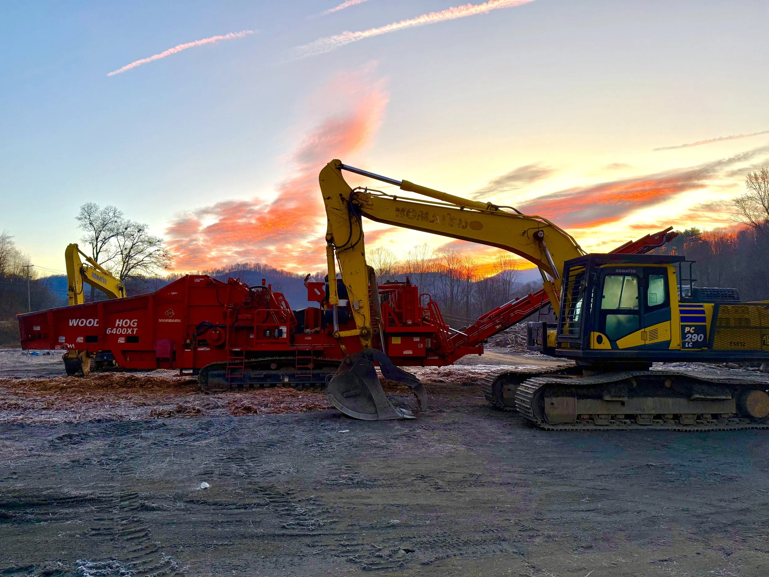 Wood grinder and excavators at a recycling yard