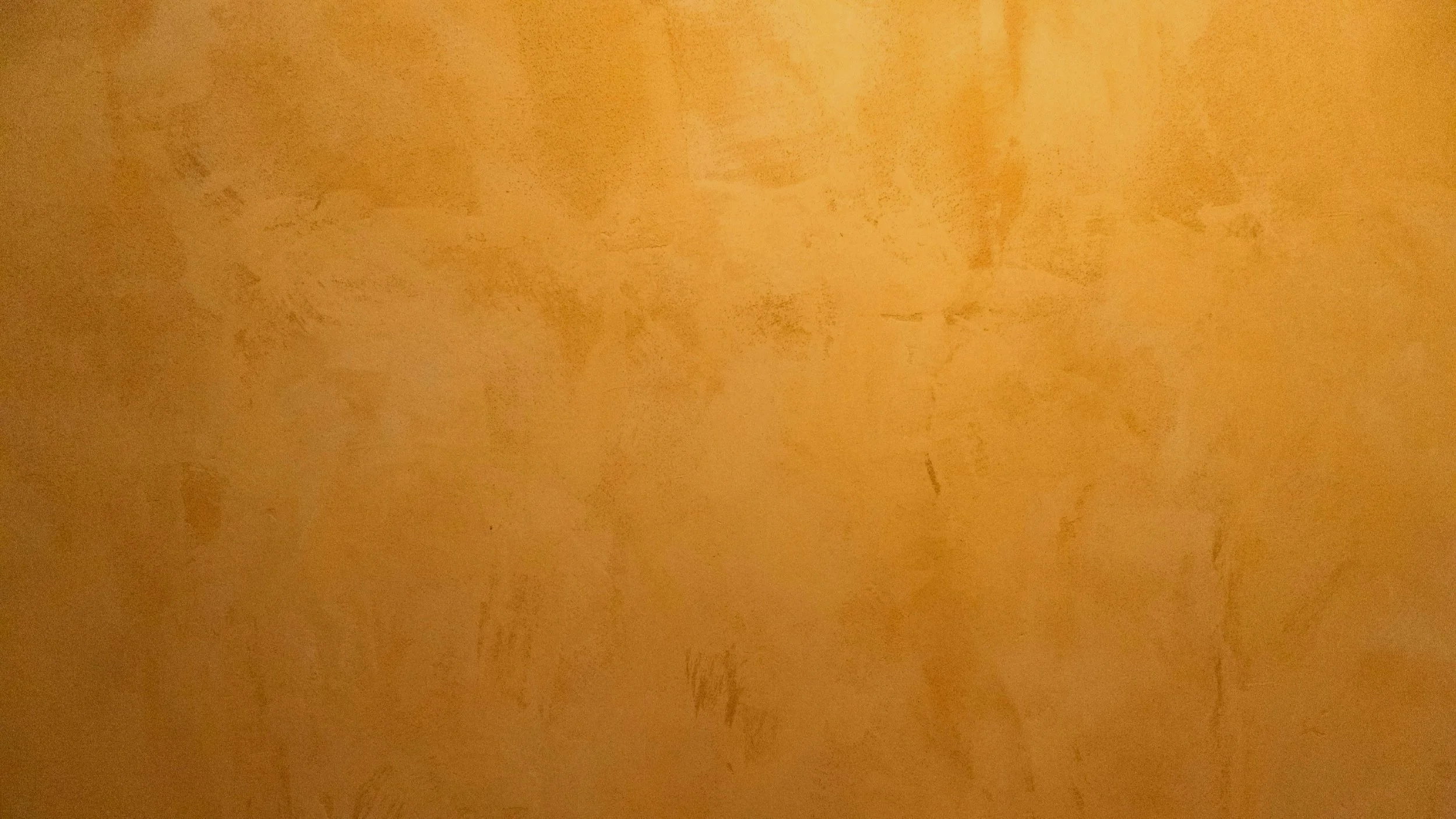 Close-up of an orange textured wall with uneven patches and marks.