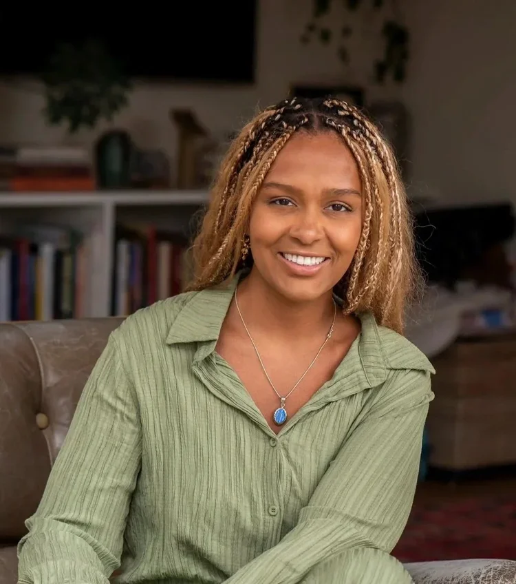 A smiling woman sitting on a couch in a cozy living room.