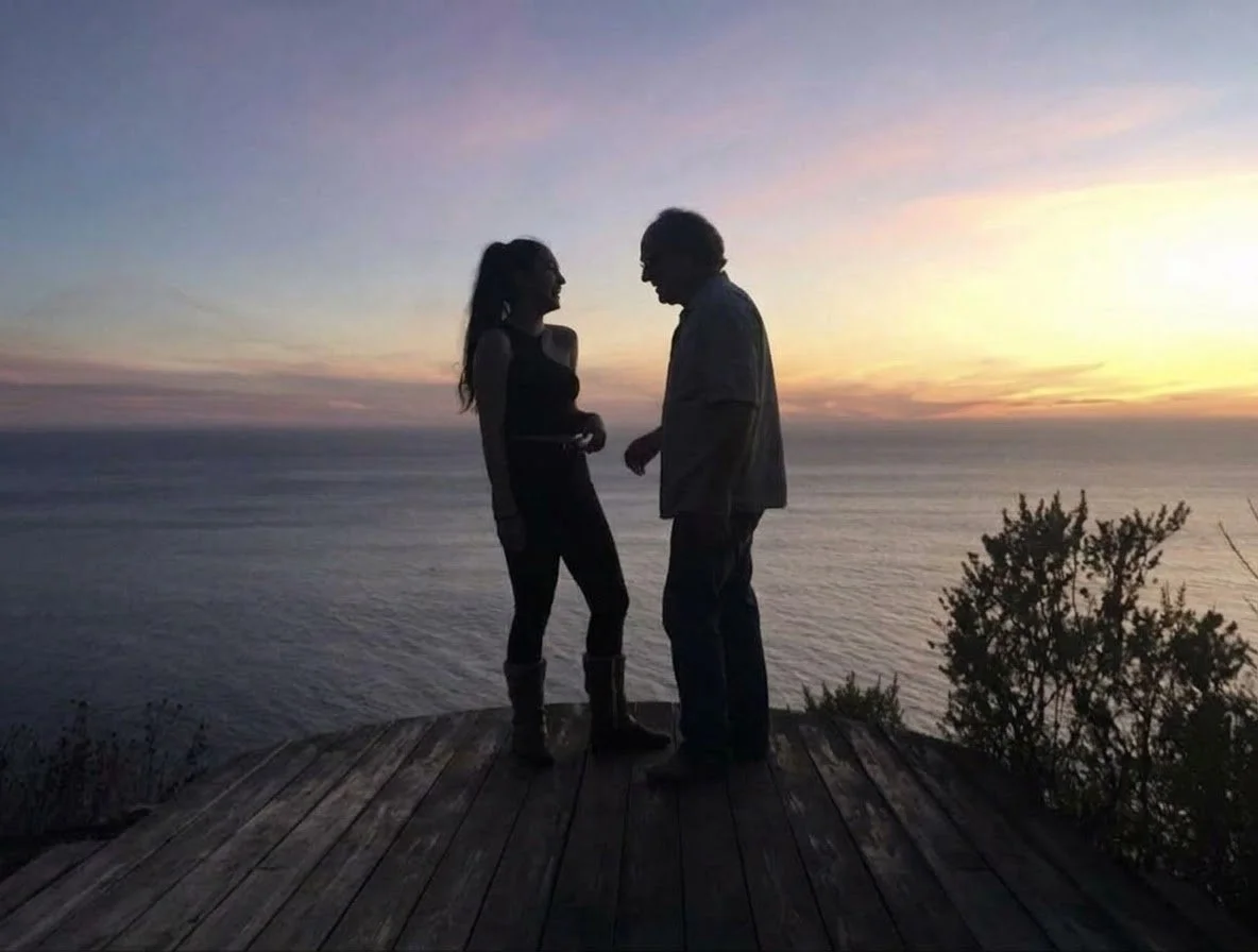 Two people in conversation overlooking the ocean at sunset. flip-target