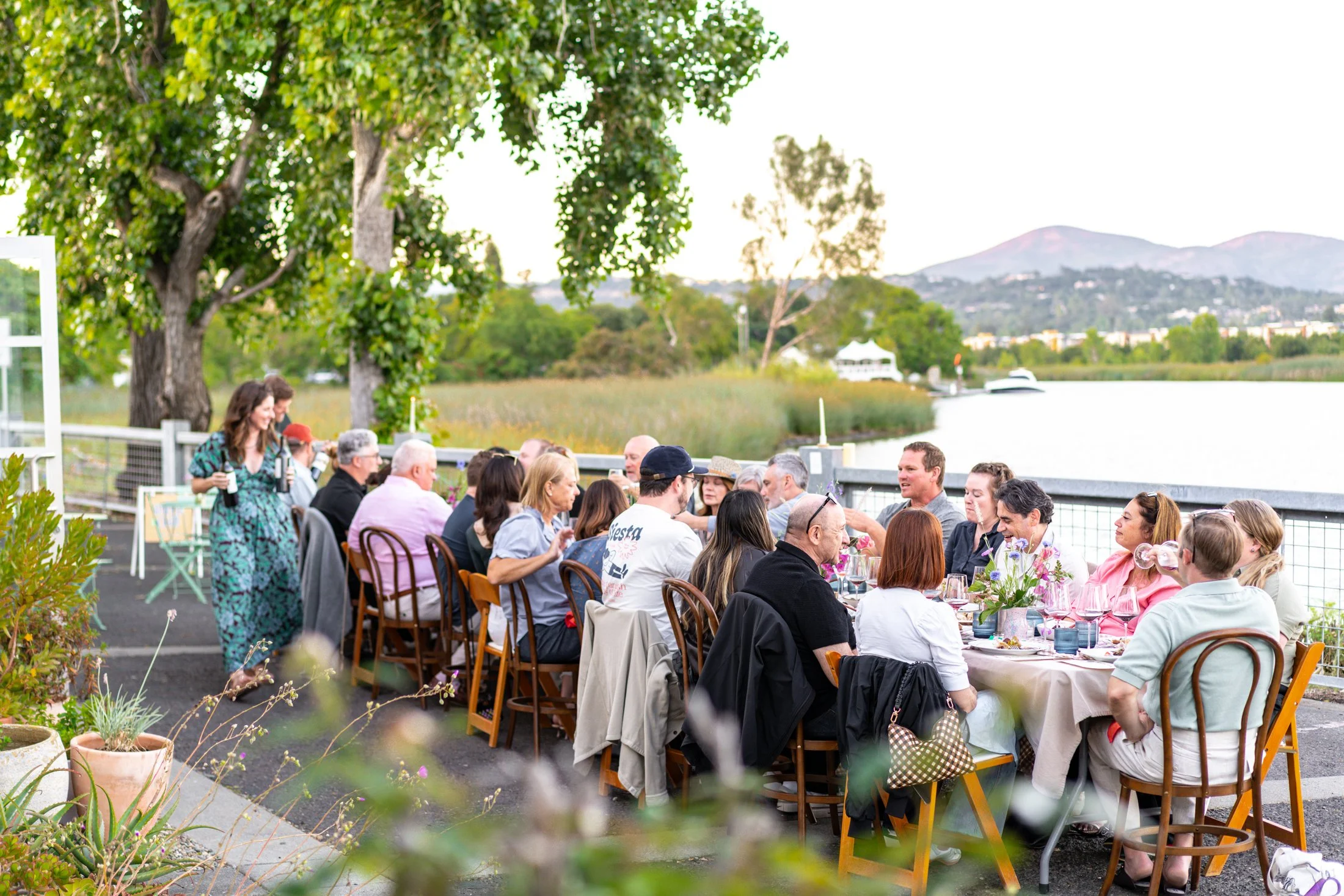 Guests dining together at a Stoop Supper Club dinner overlooking the Napa River at The River Club.