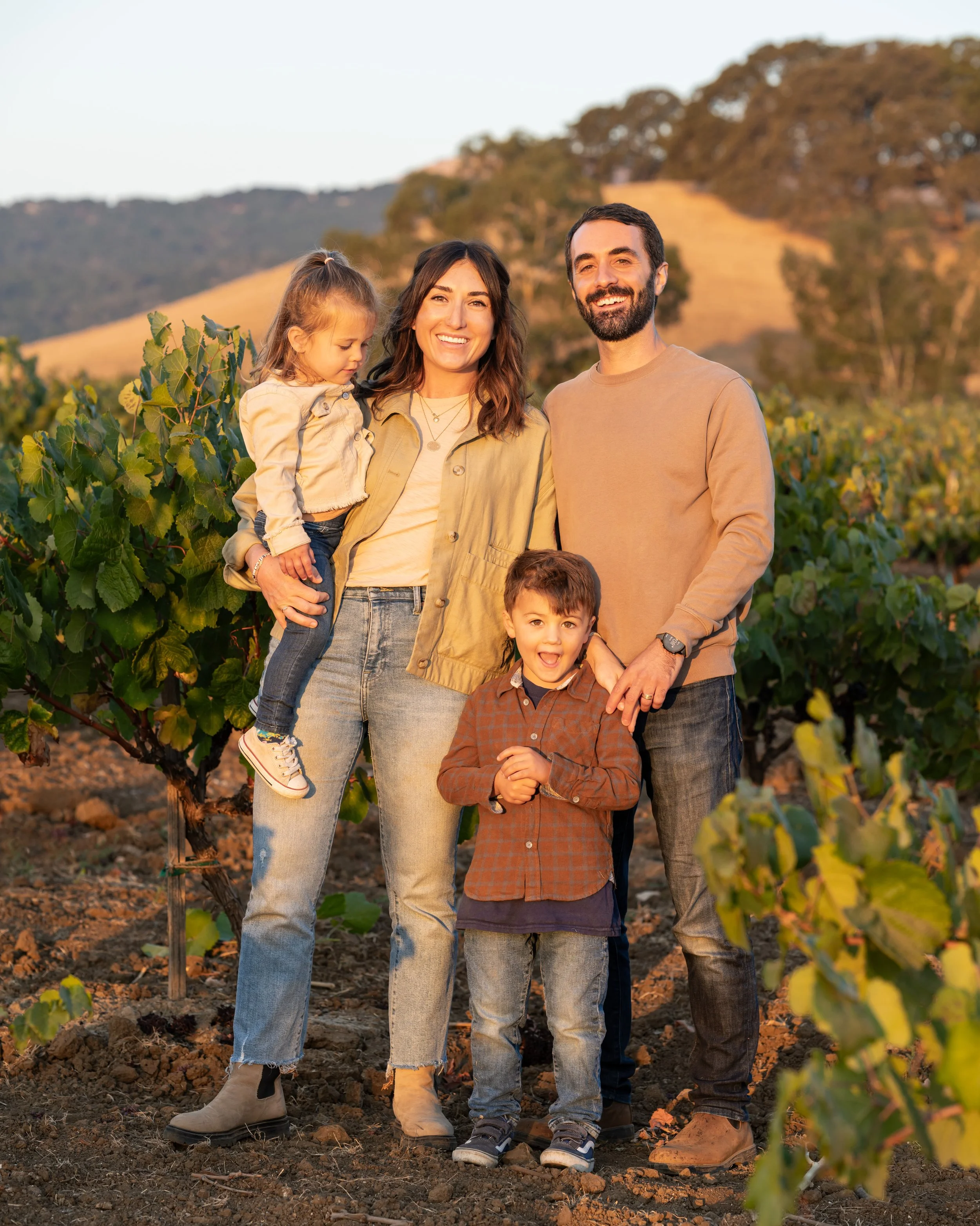 Paper Planes Wine Co. founders Kyle and Laura Gabriel with their children Noah and Ella in a vineyard.