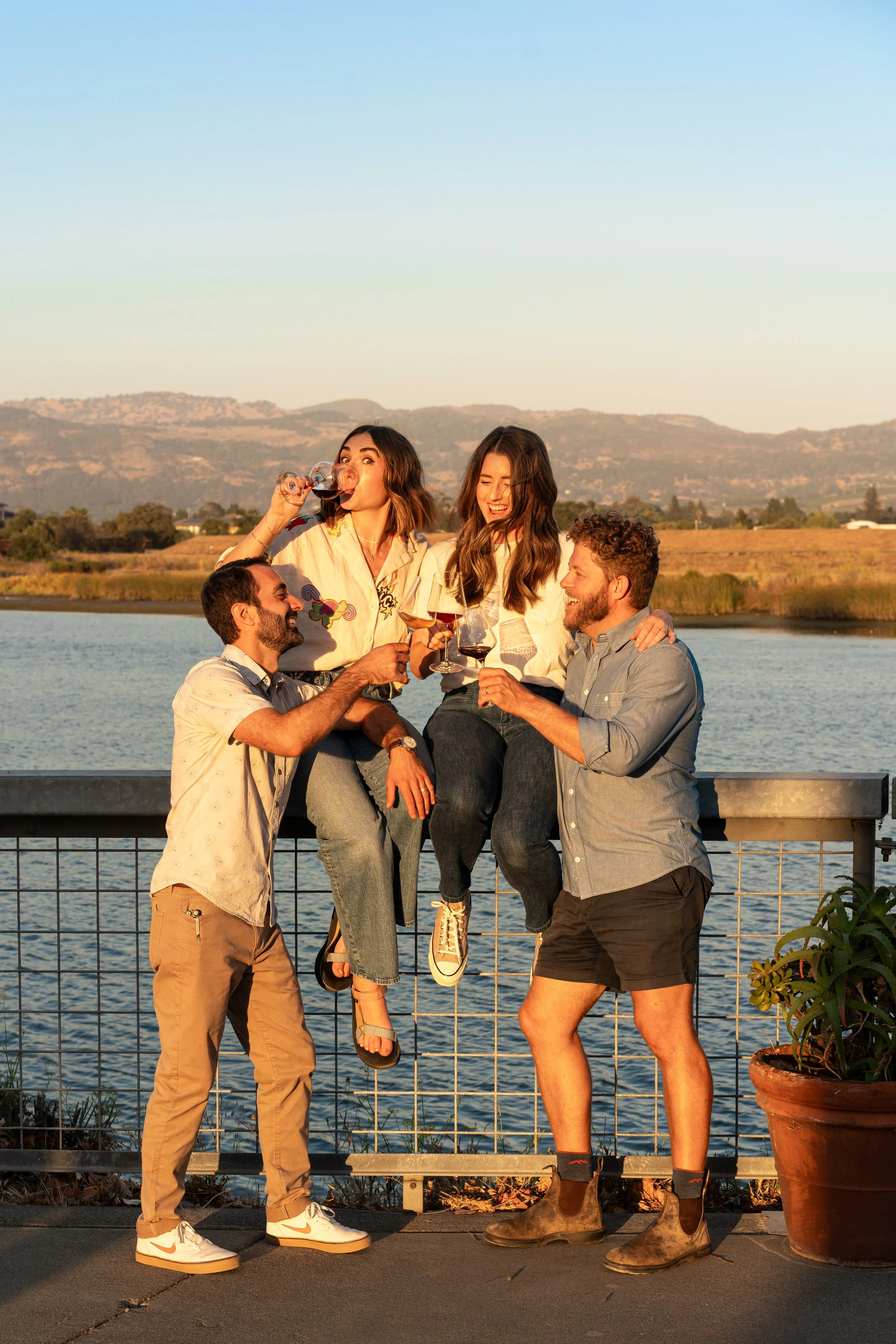 The four founders of The River Club Napa enjoying wine together at sunset along the Napa River.