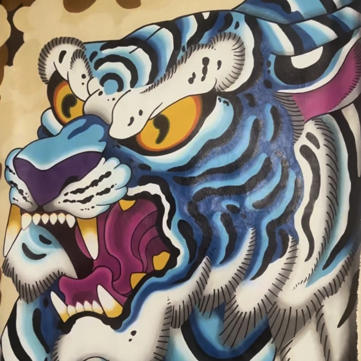 Colorful mural of a fierce tiger with bold black and blue stripes, orange eyes, and an open mouth showing sharp teeth and a pink tongue.