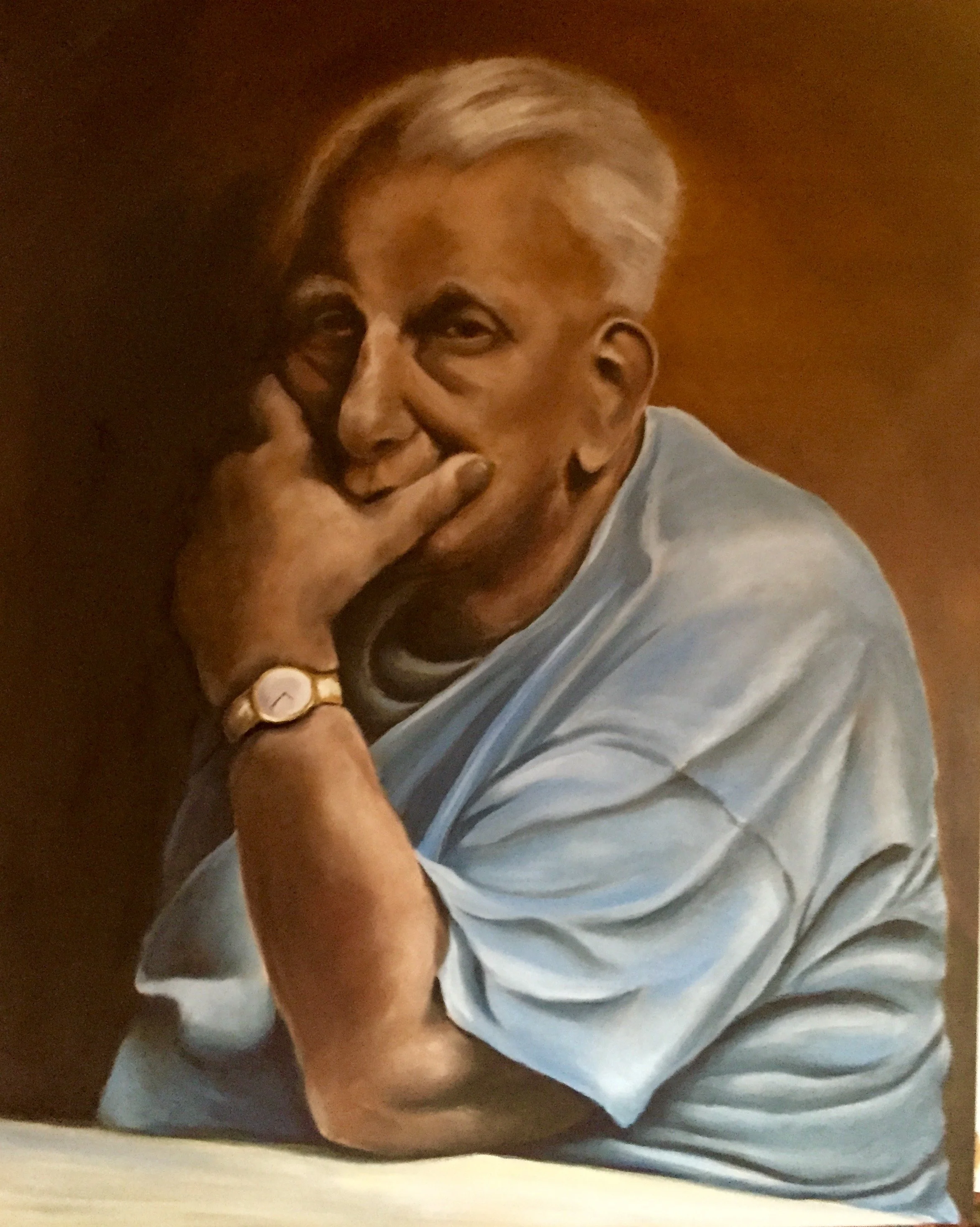 A person with platinum blonde hair, holding a cigarette near their mouth, with one eye visible, wearing a white T-shirt, and a gold watch on their wrist, sitting against a brown background.