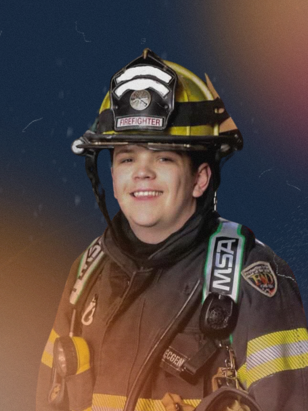 A young male firefighter wearing a helmet labeled 'FIRE FIGHTER' and firefighting gear, smiling at the camera.