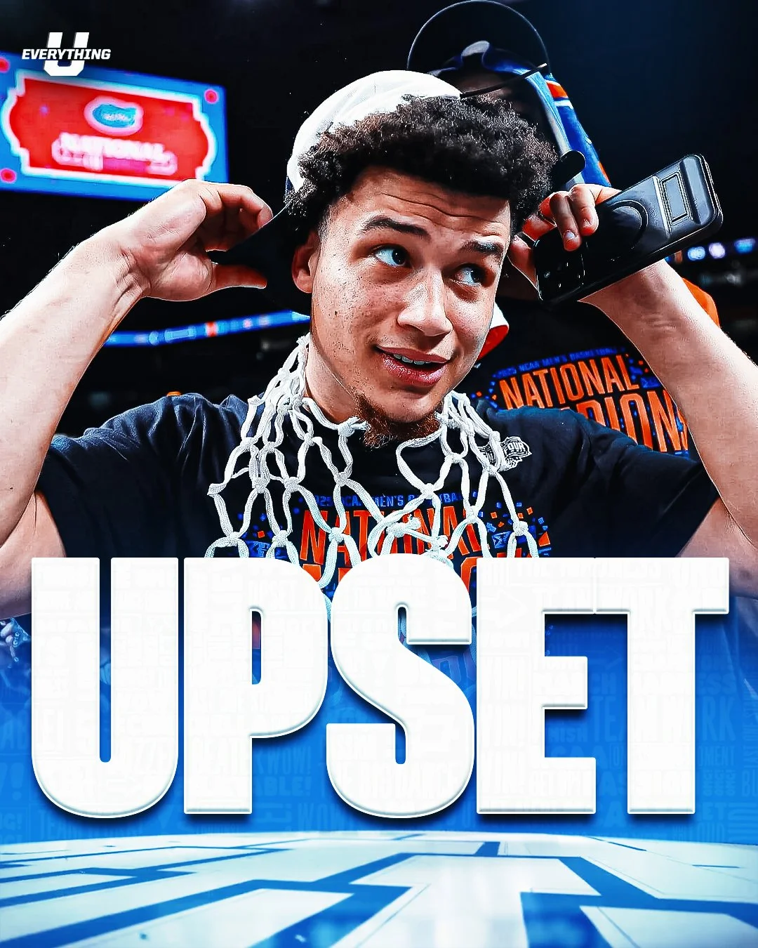 Young man with a basketball net around his neck, holding a phone to his ear, in a sports arena, celebrating a basketball victory.