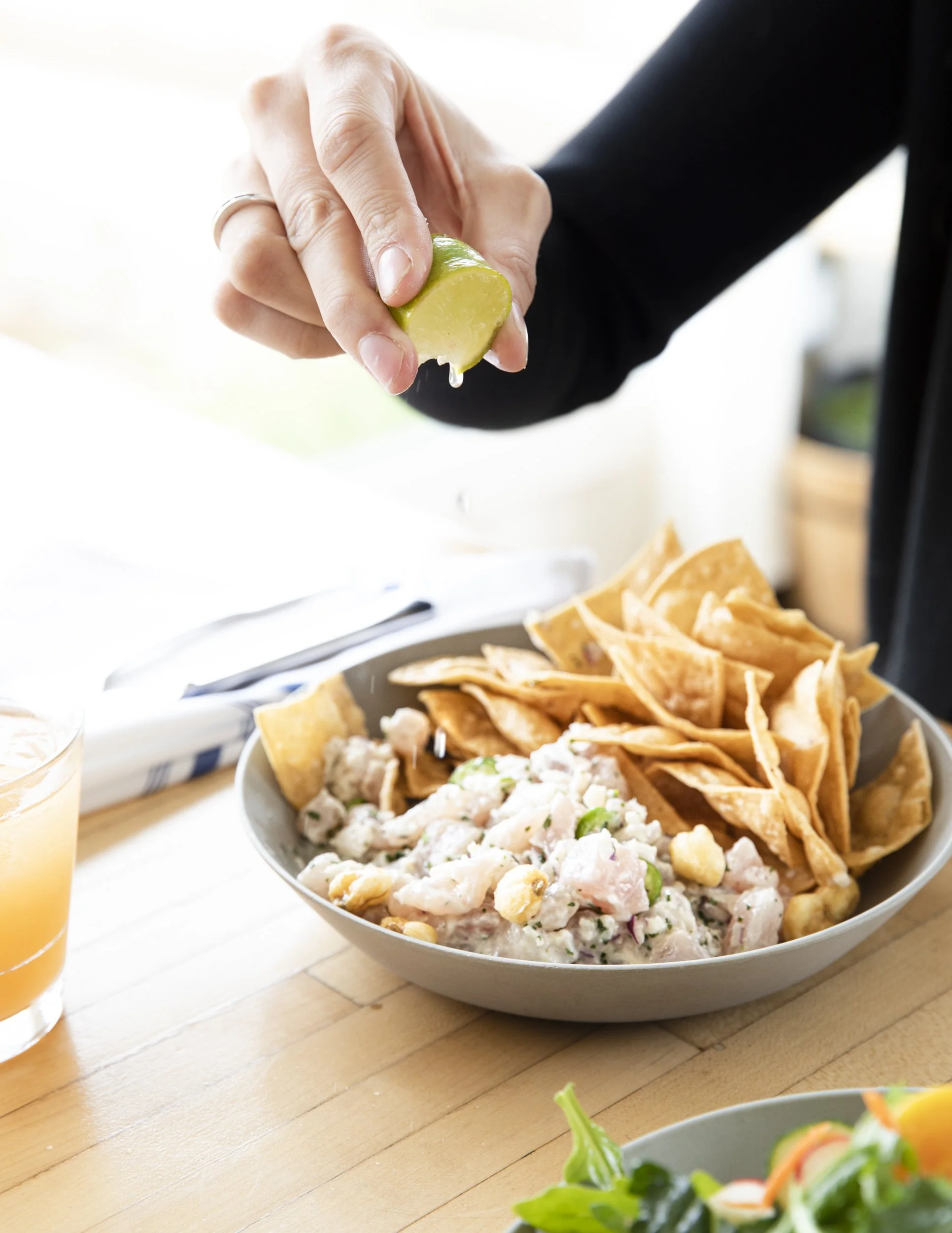 Food adventure and lifestyle photography by commercial photographer Kaare Iverson. Person squeezing lime into a bowl of ceviche on a wooden table.  Shot for Treasure Island Development Group at Mer Sea restaurant.