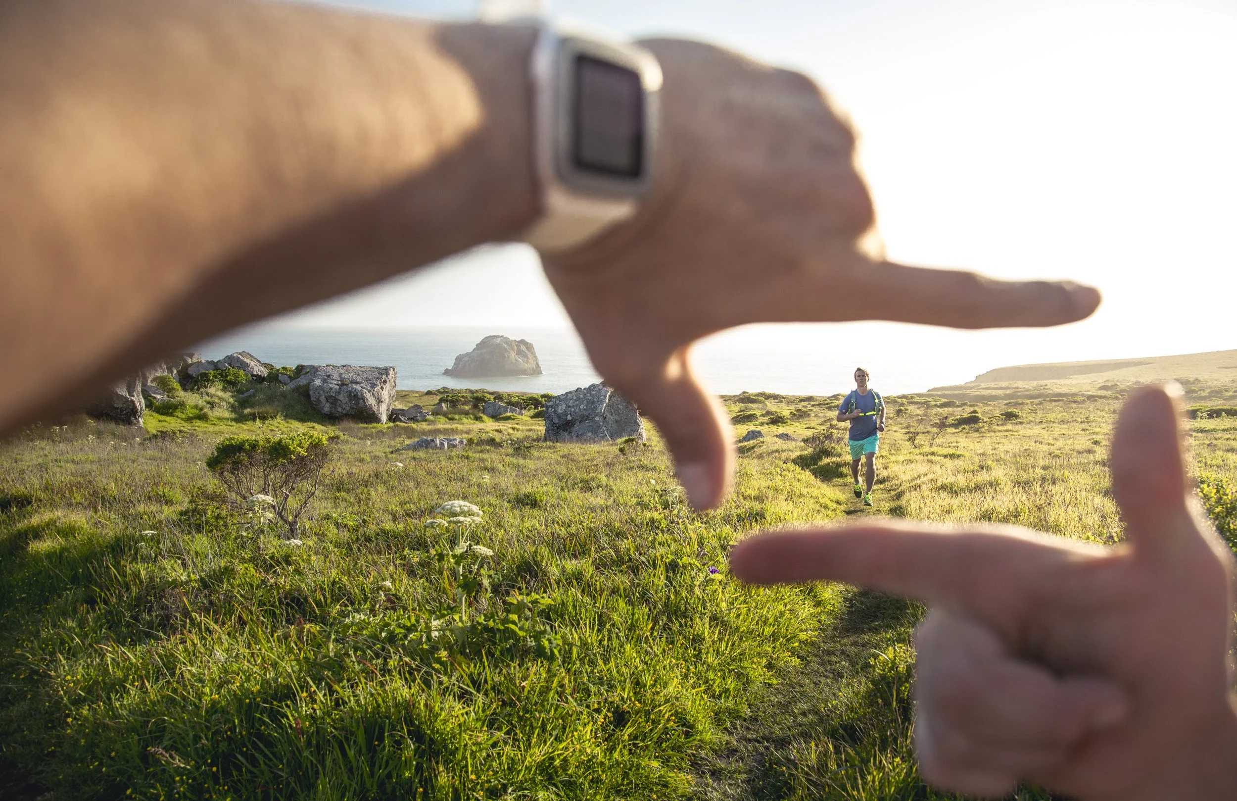 Fitness smartwatch photography by California based active lifestyle photographer Kaare Iverson.  Person wearing fitness tracker on wrist is framing up a trail runner friend with their hands at sunset