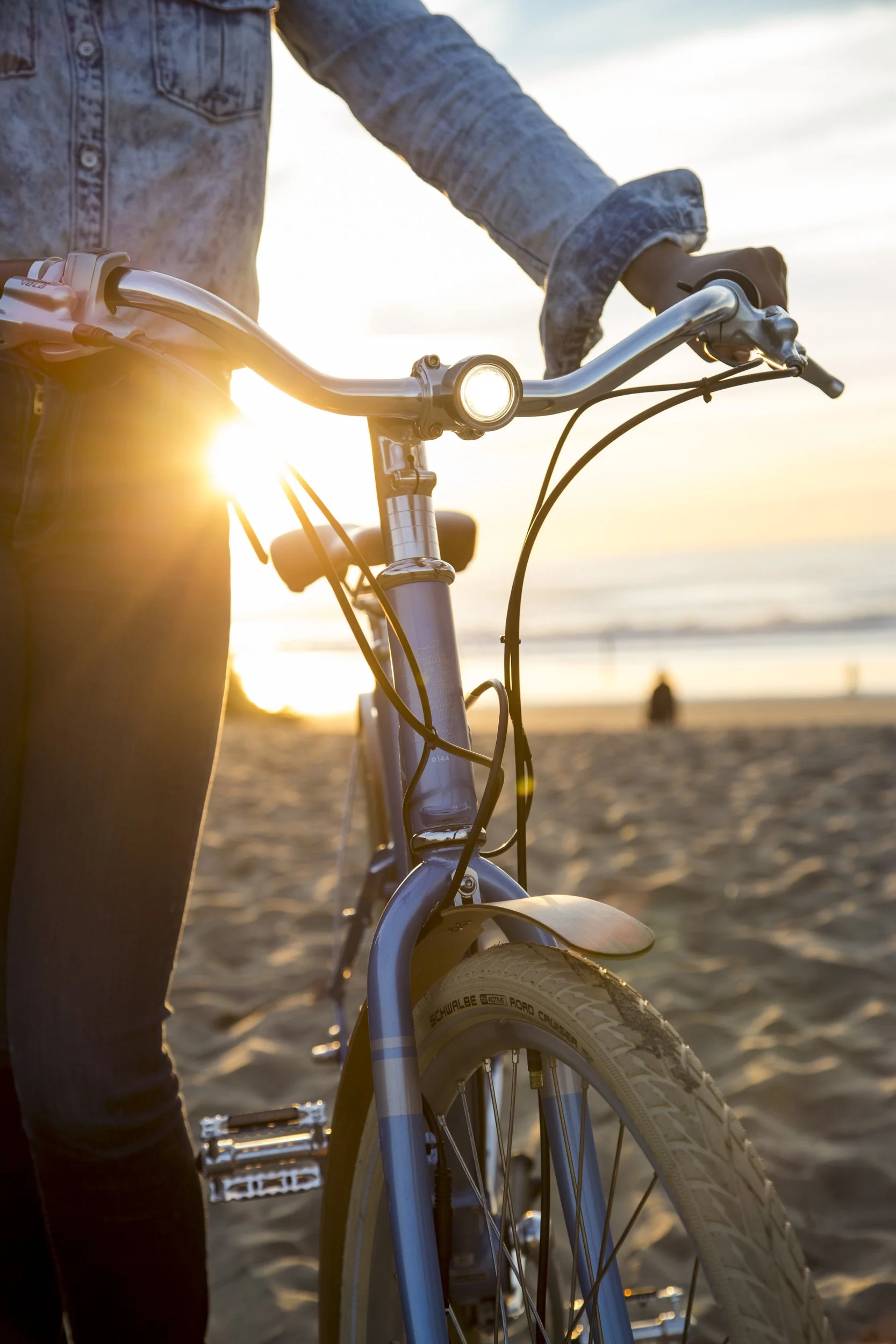 E-Bike detail photography and lifestyle image for PON Bikes shot in California by Kaare Iverson.  Bike light and cyclist hands at sunset on beach in San Francisco.