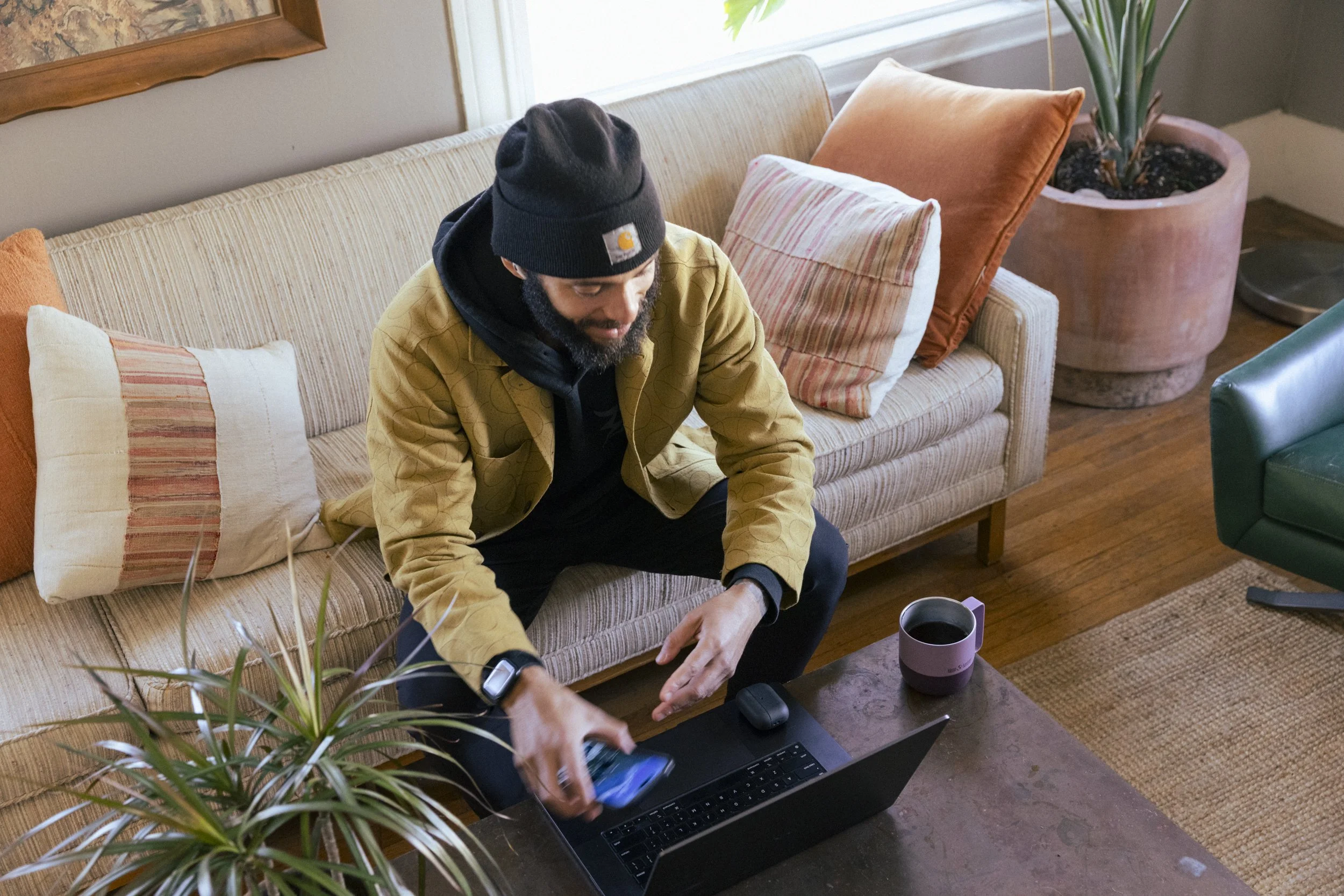 Product lifestyle photography by commercial photographer Kaare Iverson for Klean Kanteen.  Man works from home in video meeting and reaches for reusable coffee mug.