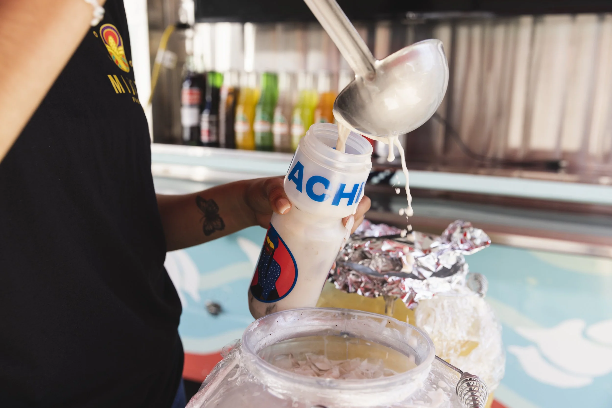 Food travel photography shot in California for Osprey Packs by commercial photographer Kaare Iverson.  Woman ladles horchata into a bicycle water bottle.