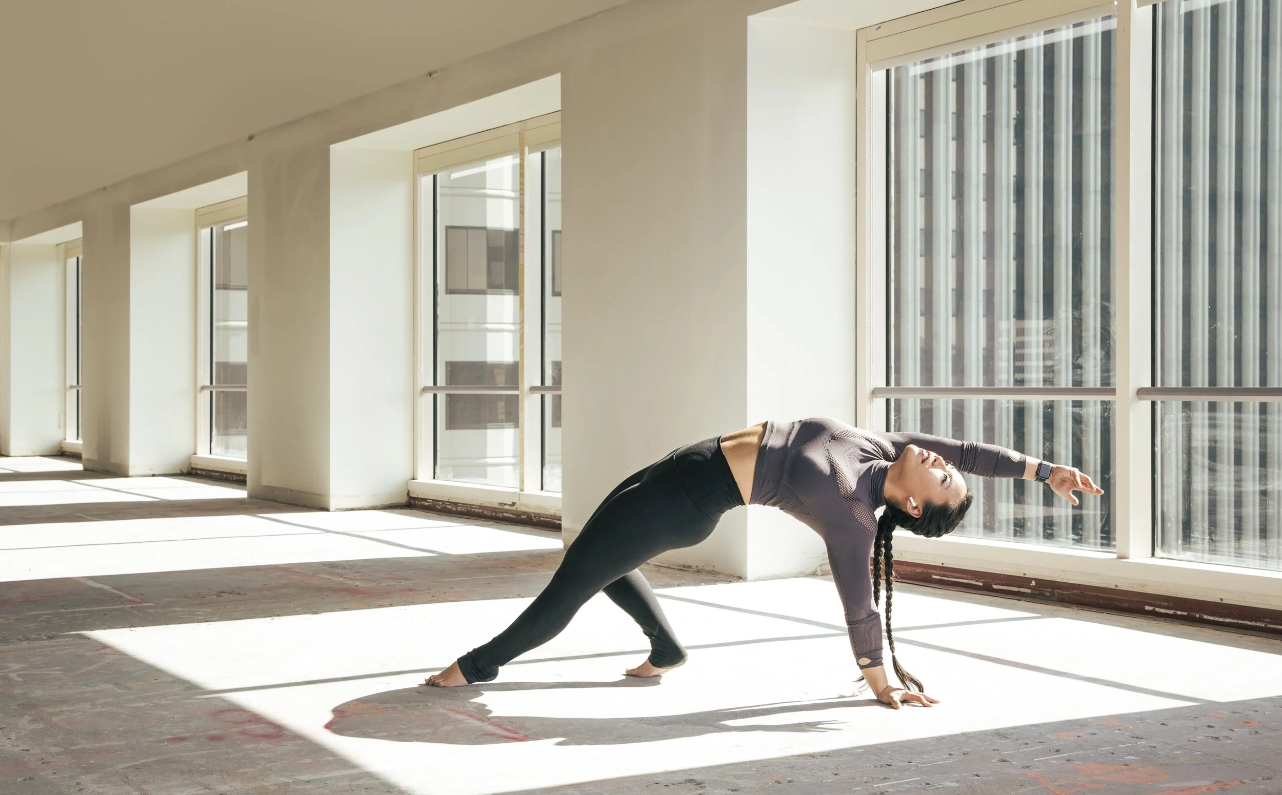Athletic fitness and training photography by Bay Area commercial photographer Kaare Iverson for Future Fit App. A woman practicing yoga indoors near large windows, doing a side stretch while in a plank pose.