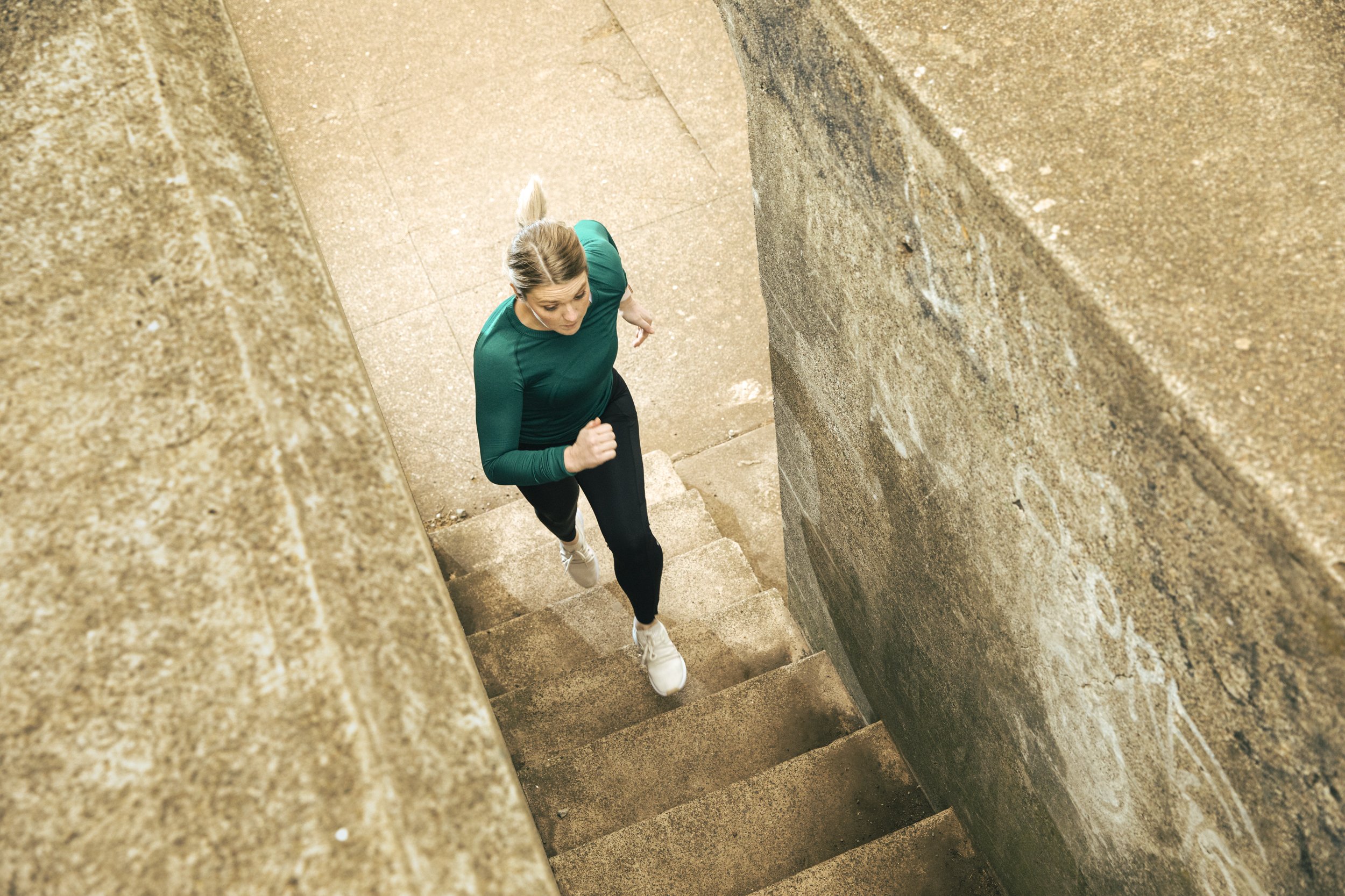 Athletic fitness and training photography for Future Fit App by Bay Area commercial photographer Kaare Iverson. A woman running stairs between stone walls.