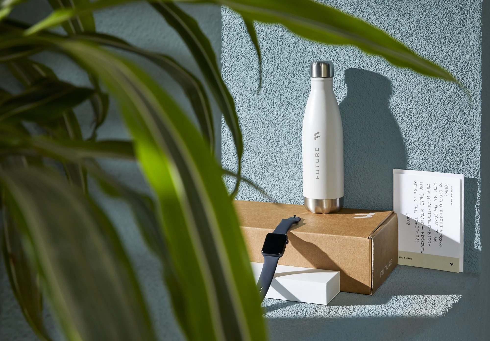Technology and subscription photography by California commercial photographer Kaare Iverson. Product lifestyle Future welcome kits featuring smartwatch, water bottle, and personalized note from trainer on a shelf.