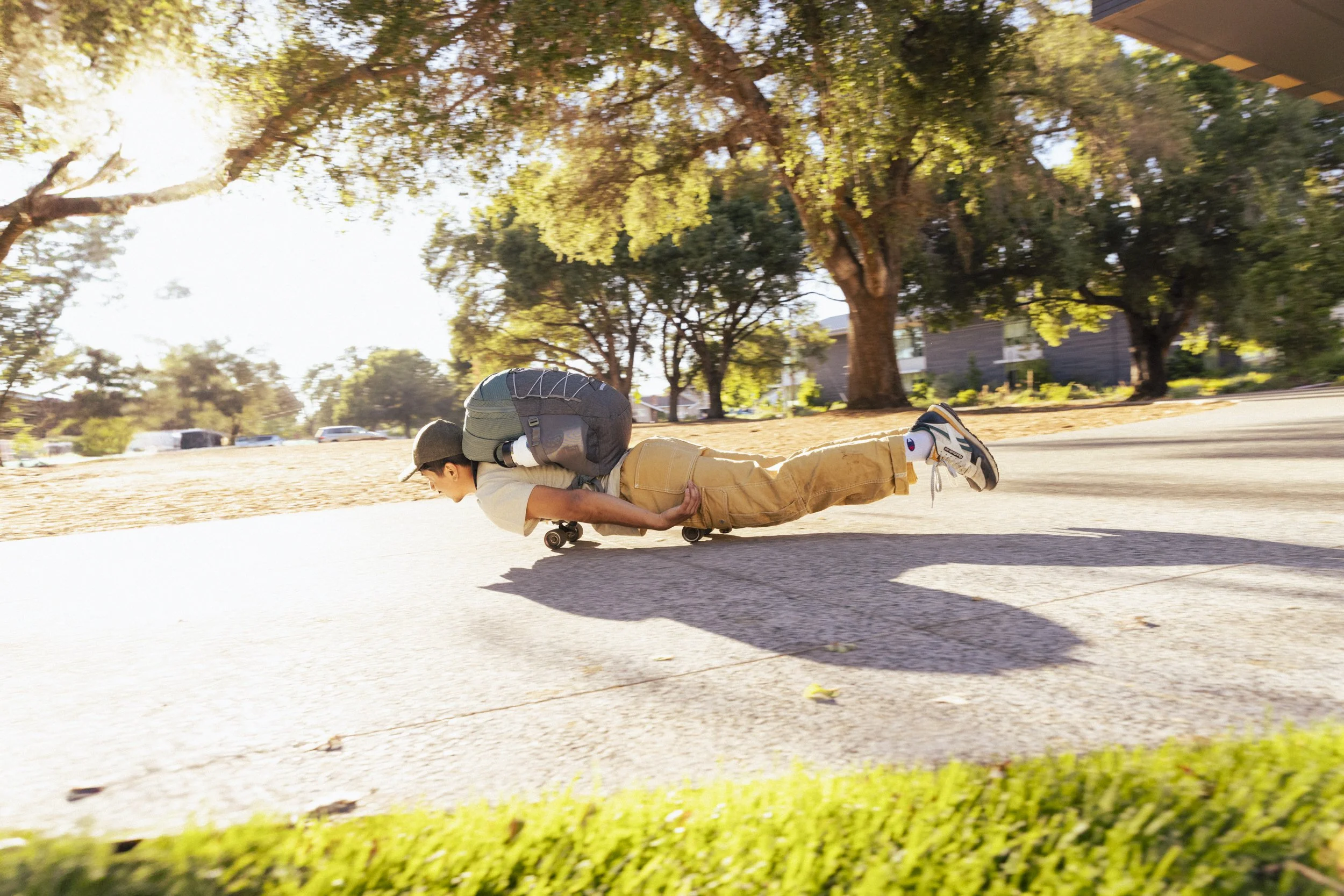 Energetic youth college lifestyle photography by California commercial photographer Kaare Iverson. A person body luging a skateboard with an Osprey backpack on.