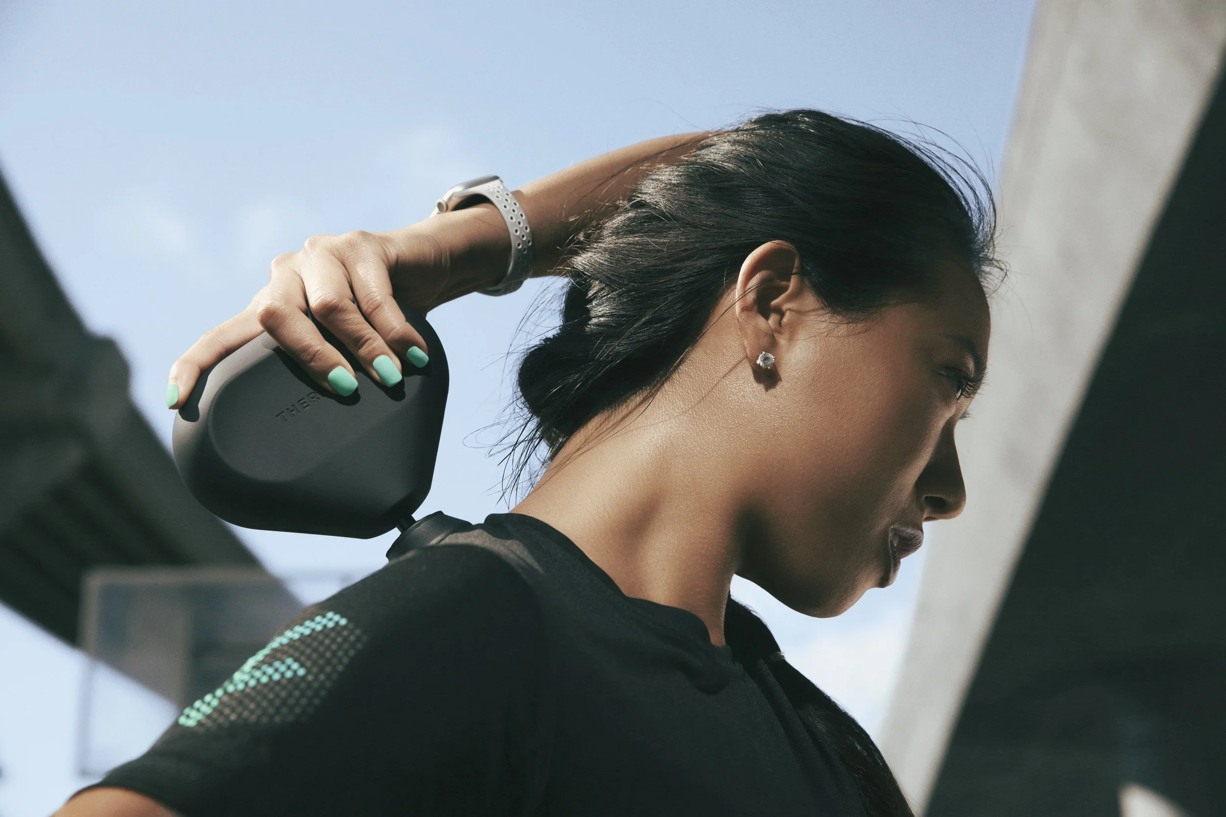 Fitness and health product photography by California commercial photographer Kaare Iverson for Future Fit App. A woman using a Theragun in an urban setting.
