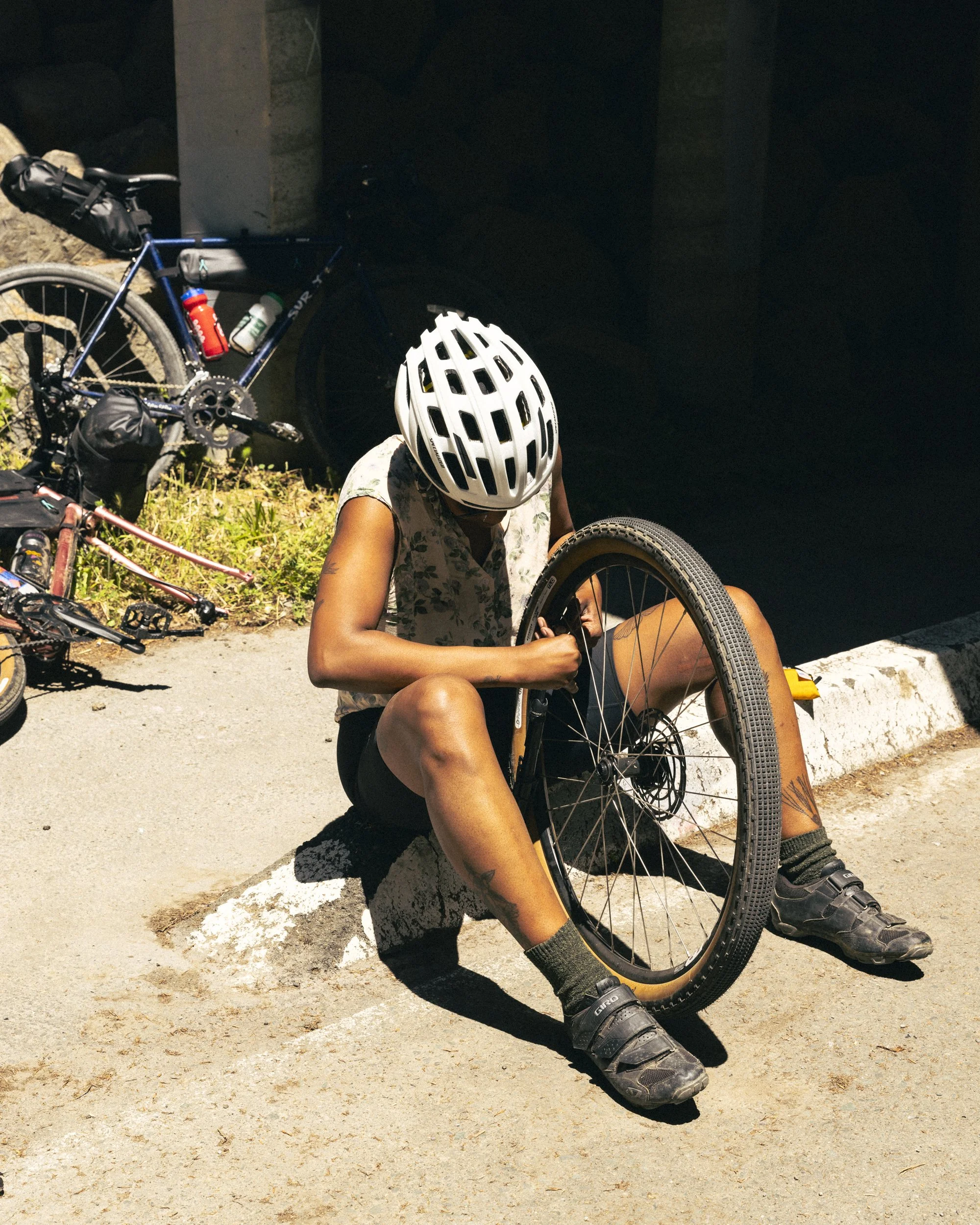 Product lifestyle photography of frame bag kit from Osprey Packs by California commercial photographer Kaare Iverson. Woman works on bike wheel in high noon sun.
