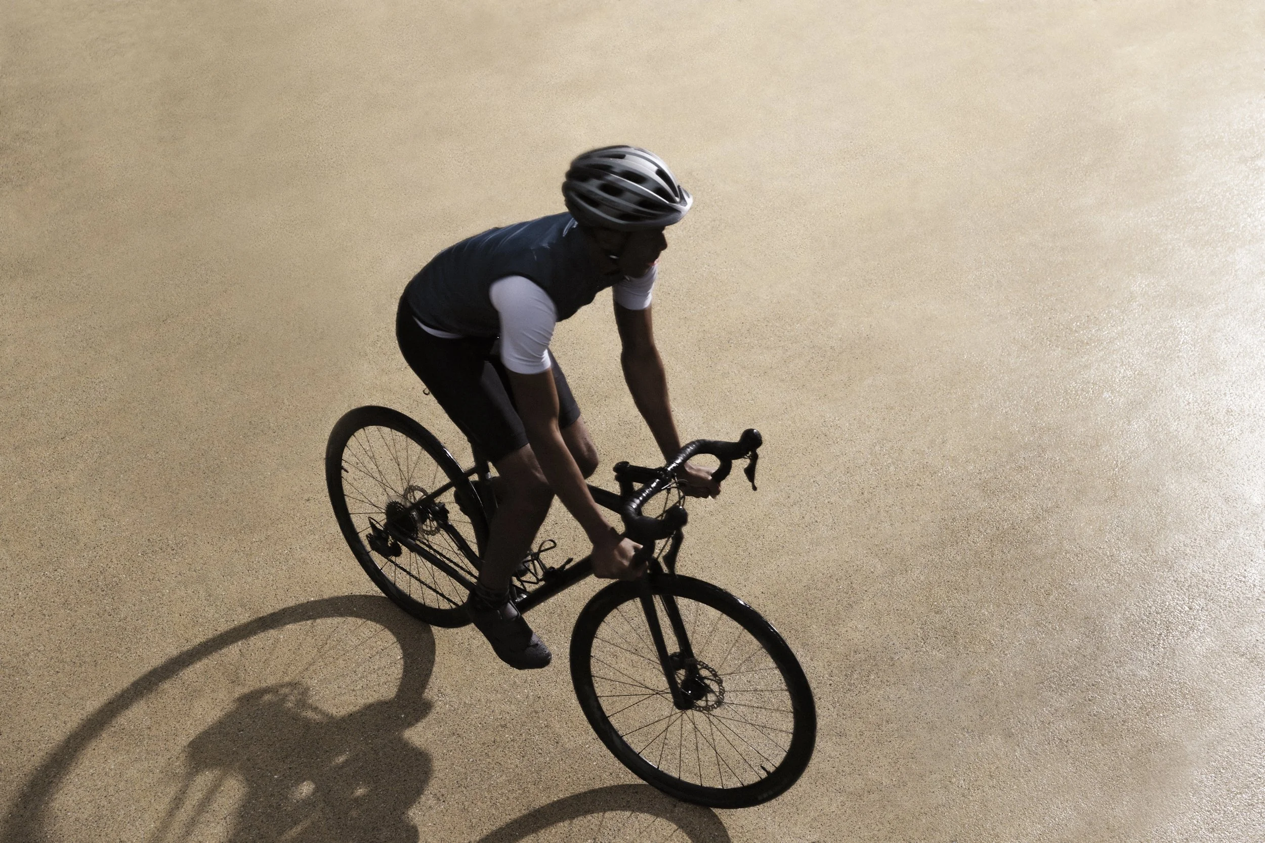 Lifestyle photography for San Francisco's Treasure Island Development by California-based commercial photographer Kaare Iverson. Silhouette of a person riding a black road bicycle on a sandy or gravel surface.