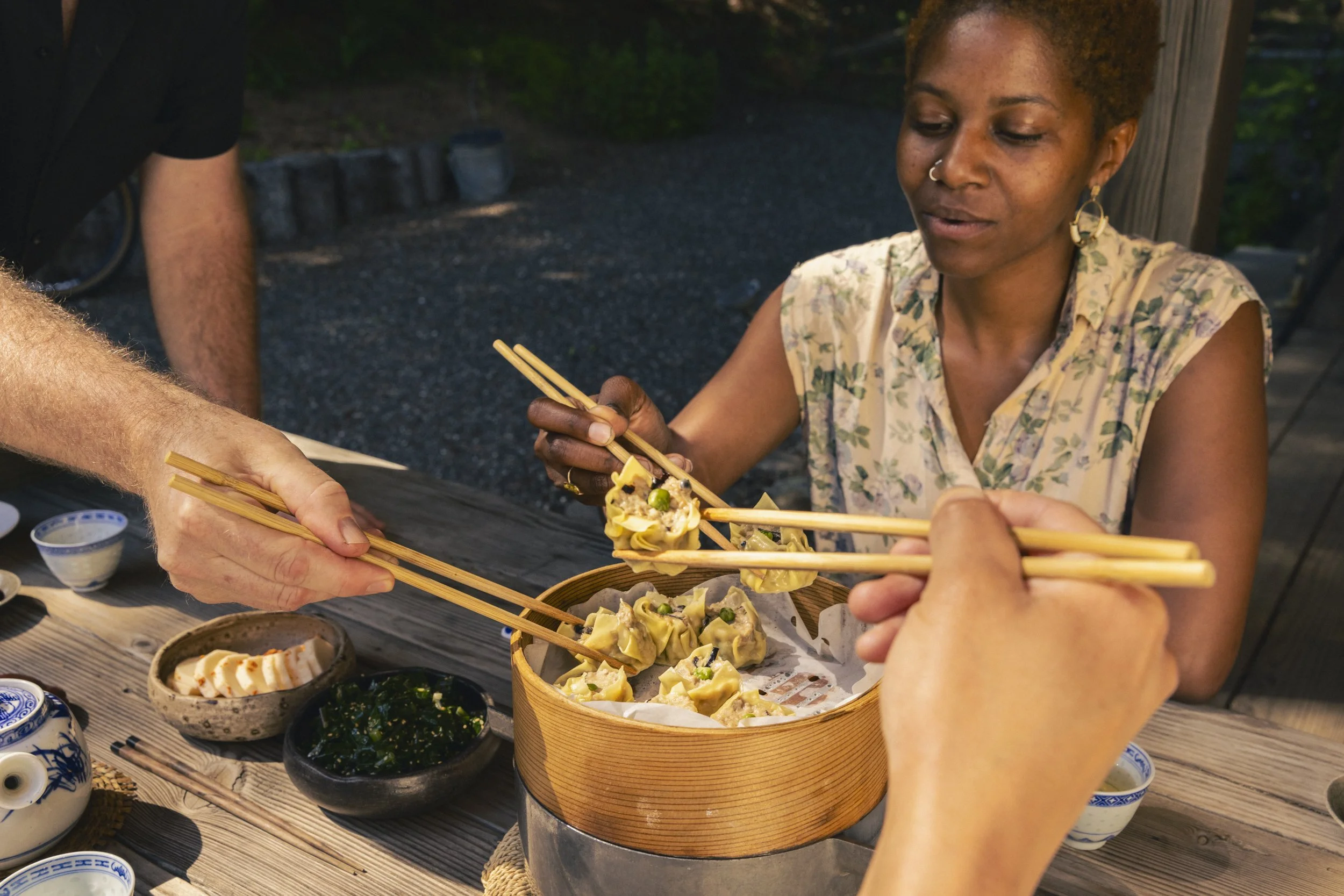 Food travel photography shot in California for Osprey Packs. People sharing dumplings using chopsticks at an outdoor dining table.  Shot by commercial photographer Kaare Iverson.