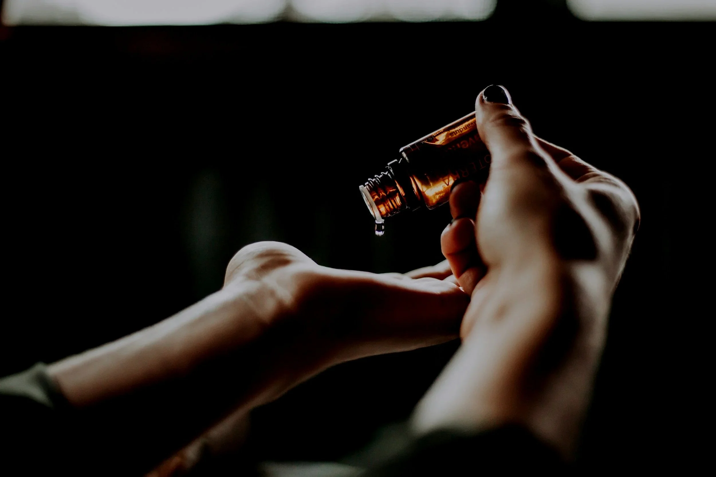 Hand holding a small vial with liquid inside.