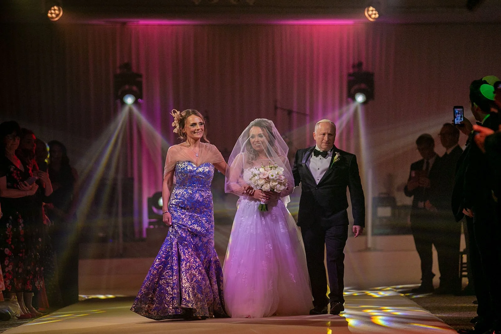 bride and parents walk down aisle during wedding ceremony at mere golf resort in cheshire