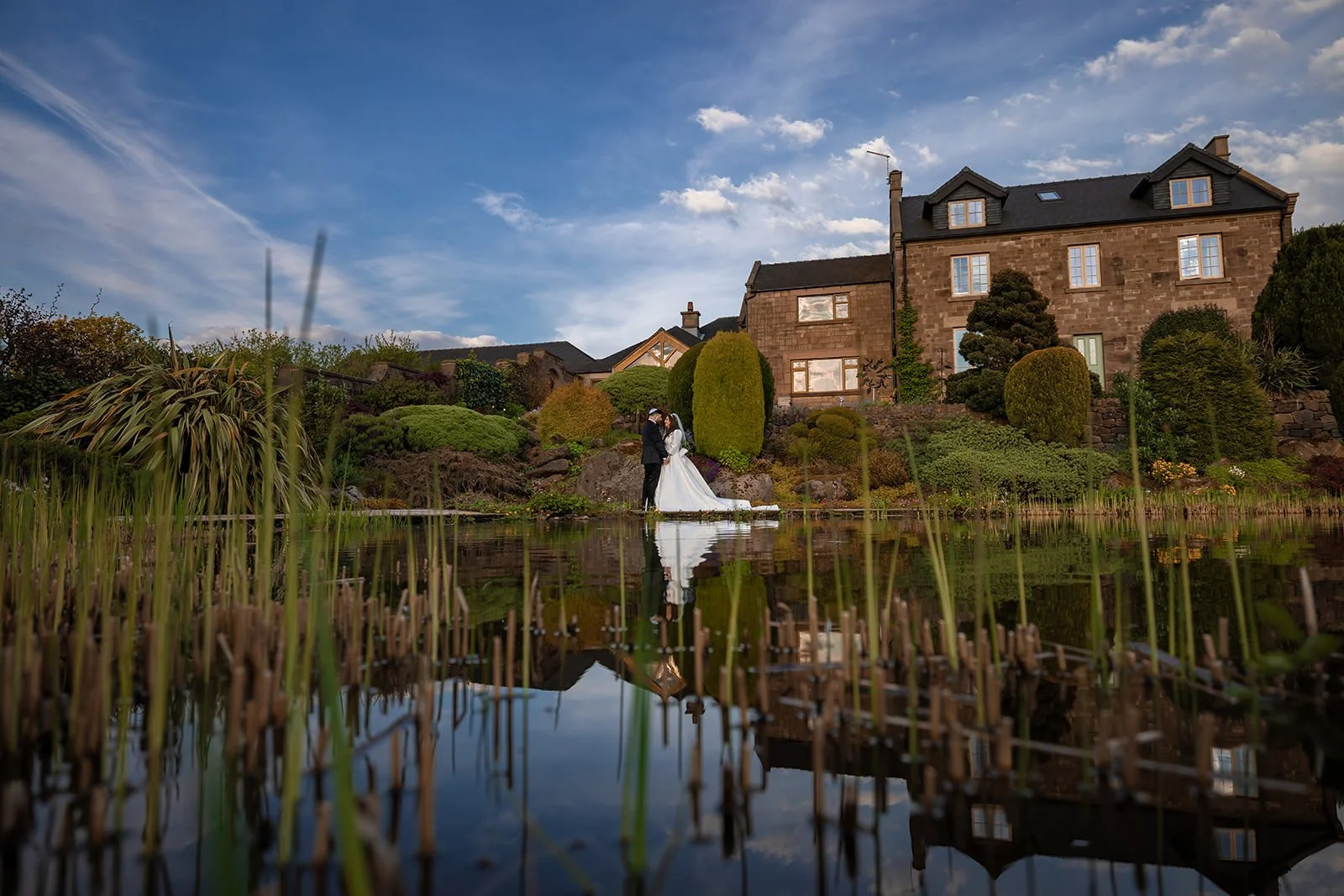 romantic bride groom newlywed couple portrait with reflection in pond in secret garden at heaton house farm in macclesfield