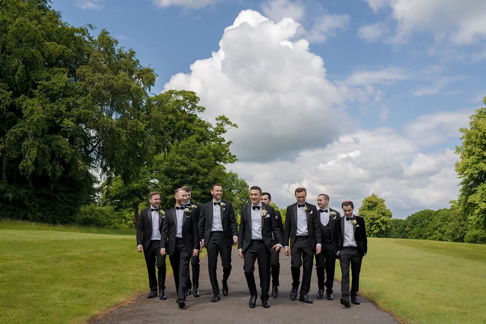 Groomsmen walking in black tuxedos on the golf course at Fairmont Cheshire - The Mere