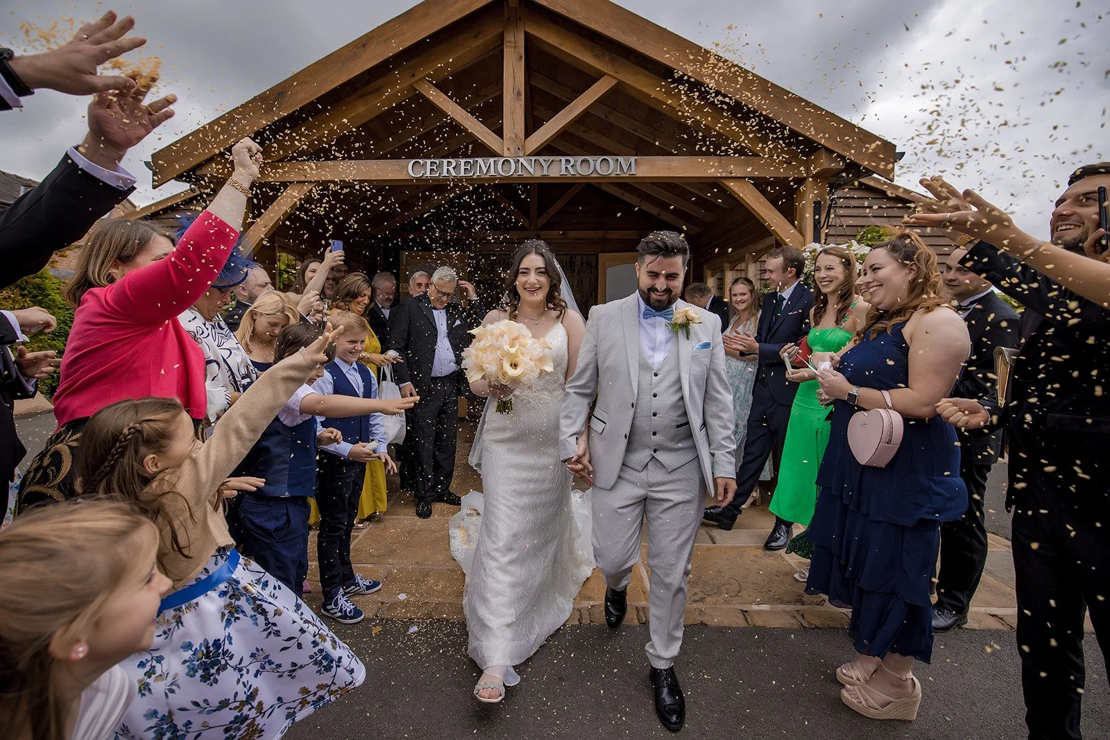 Bride and groom laughing during the confetti exit along the driveway at Merrydale Manor