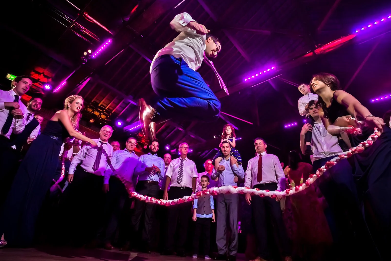 Manchester Jewish wedding photographer photograph of jewish groom skipping over rope while dancing on the dance floor