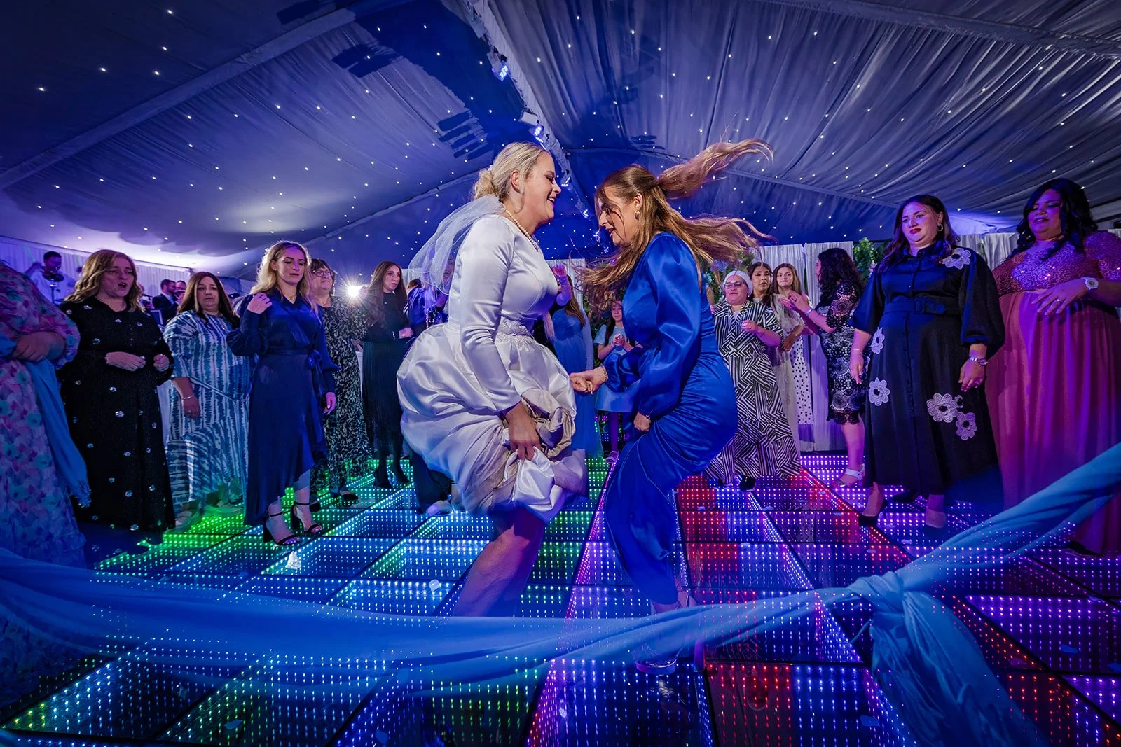 Jumping on illuminated LED dance floor at Nunsmere Hall Jewish wedding
