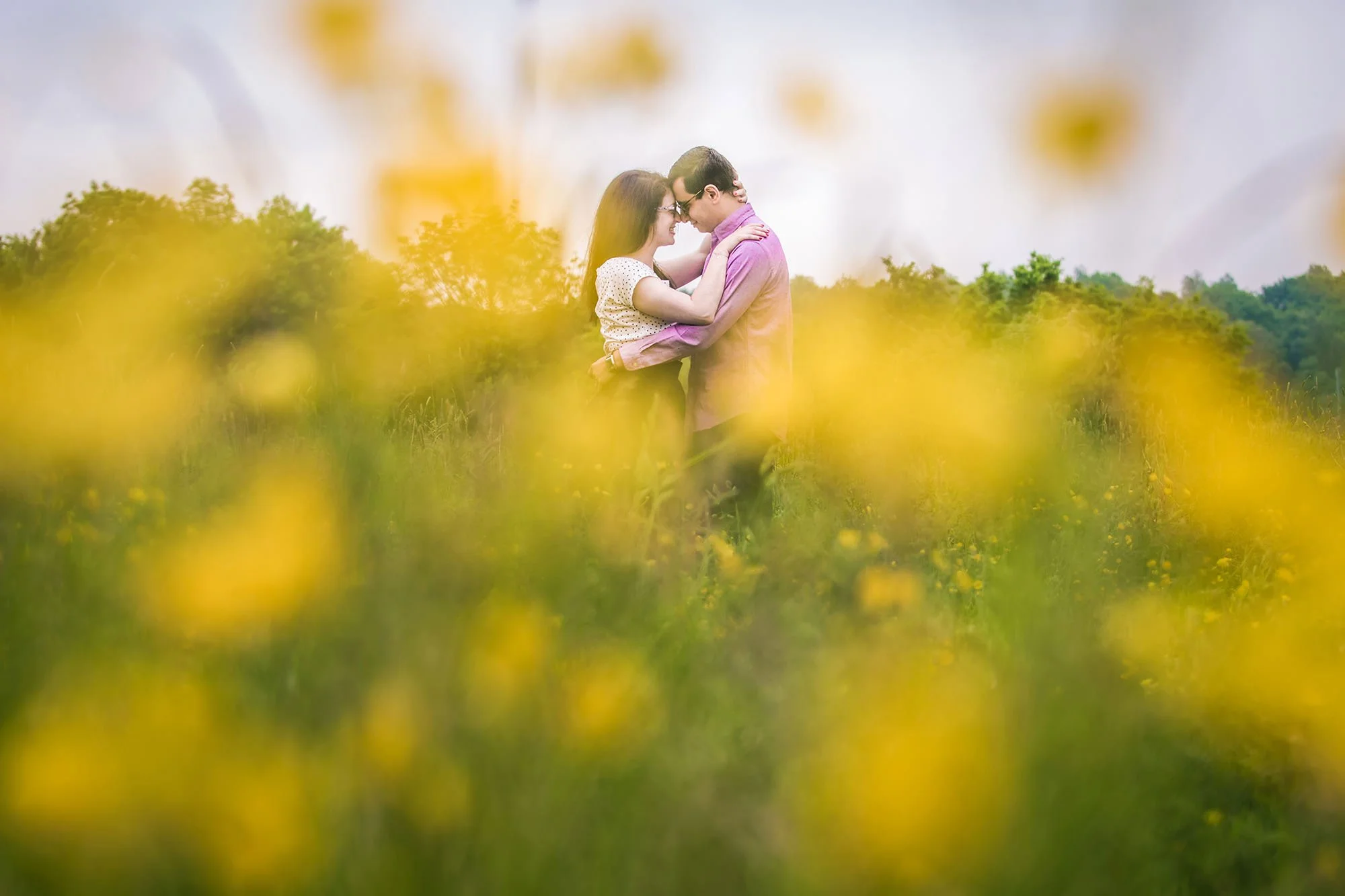 romantic couple portrait on engagement shoot looking through flowers in heaton park manchester