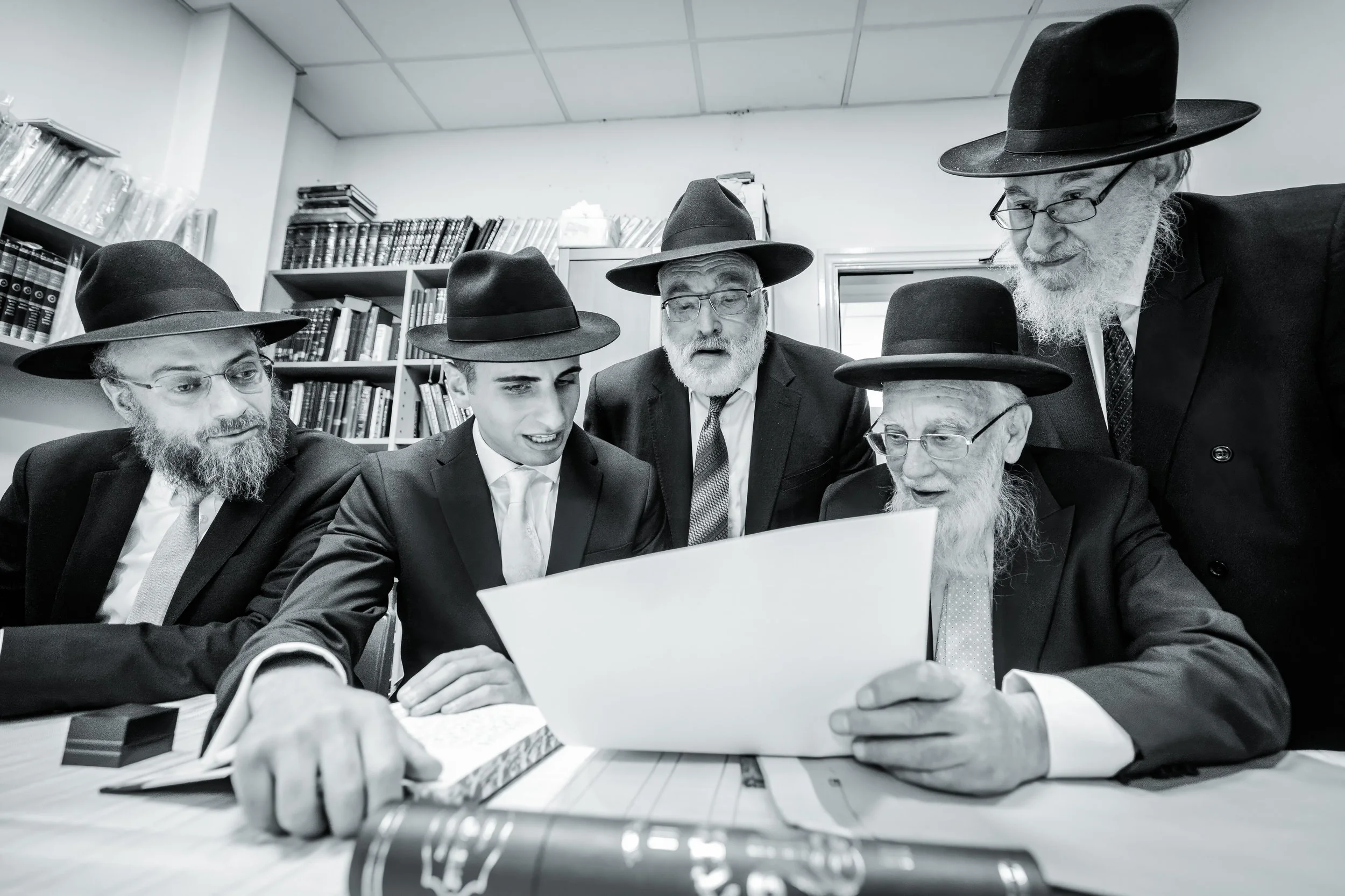 Groom and rabbis look over ketubah at tish during jewish wedding