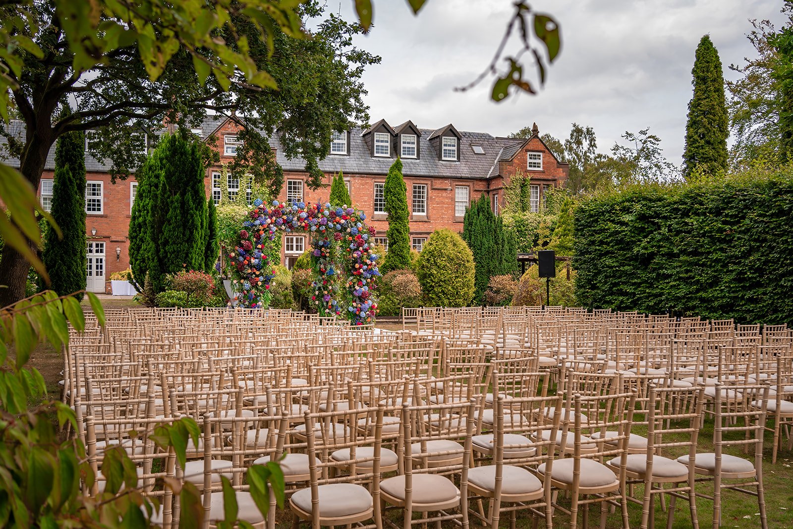 Cross-back chairs and white aisle runner for outdoor ceremony, Nunsmere Hall gardens
