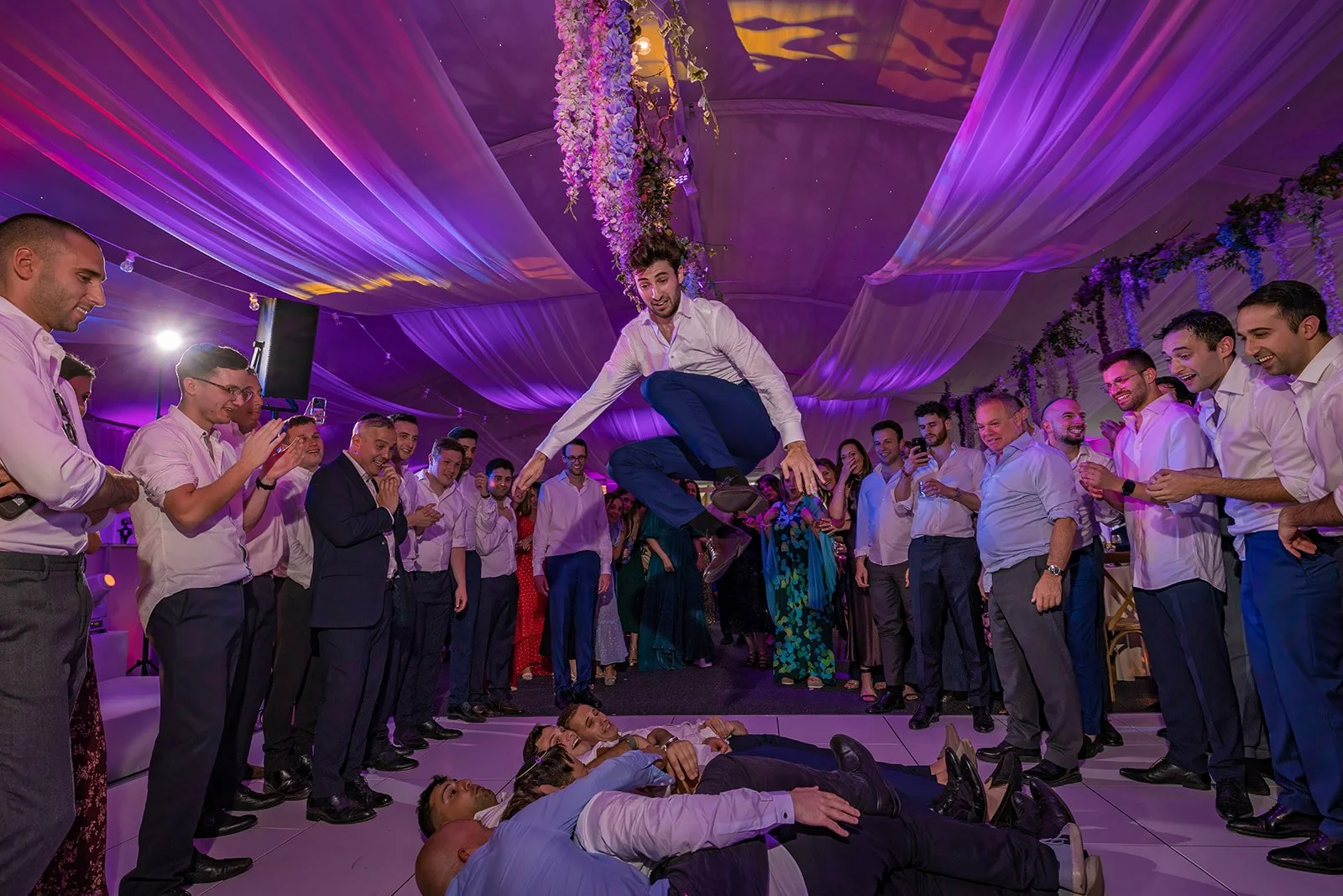 groom jumping over friends at Nunsmere Hall Jewish wedding reception