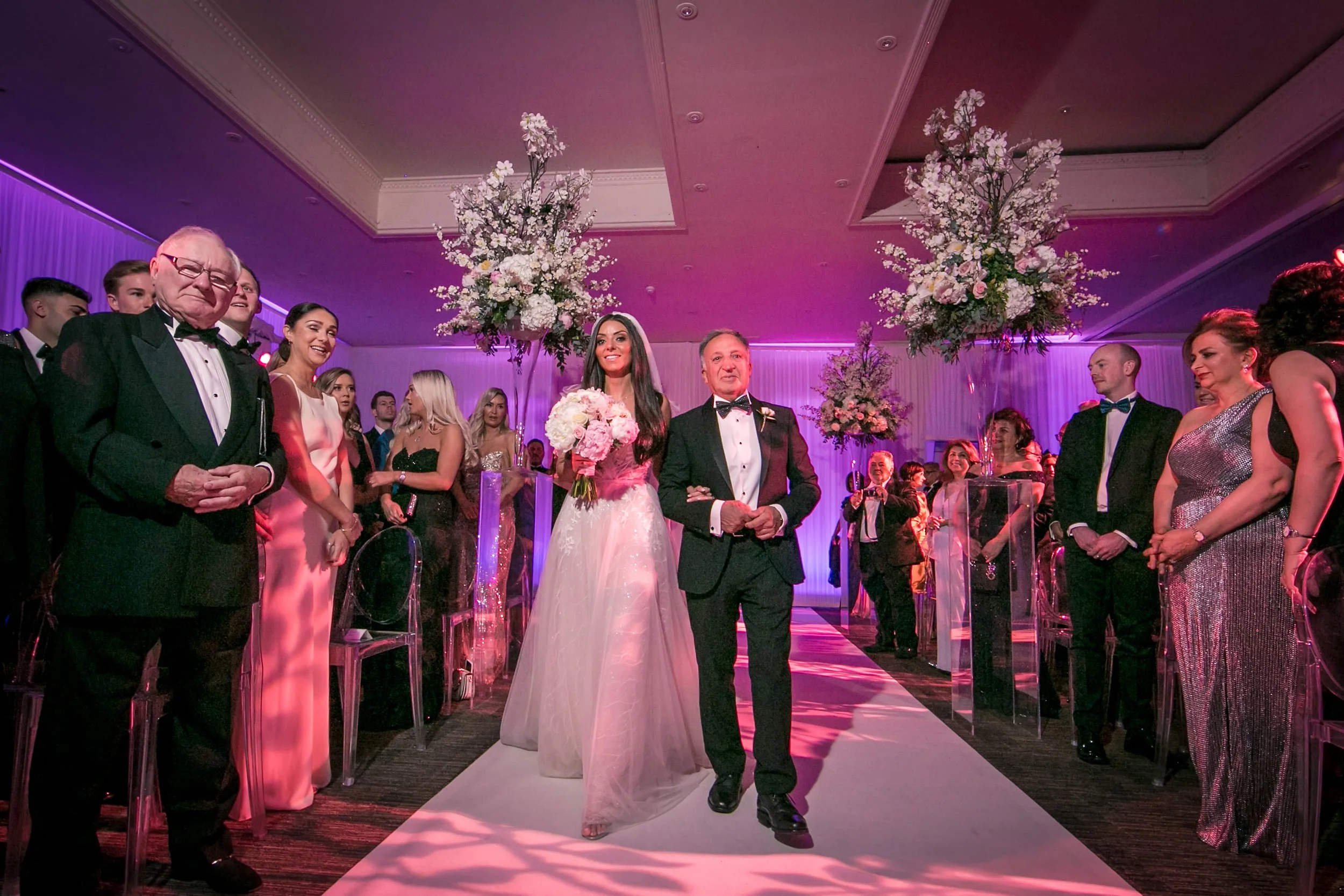 Bride walking down the aisle under pink lighting, The Mere Knutsford

