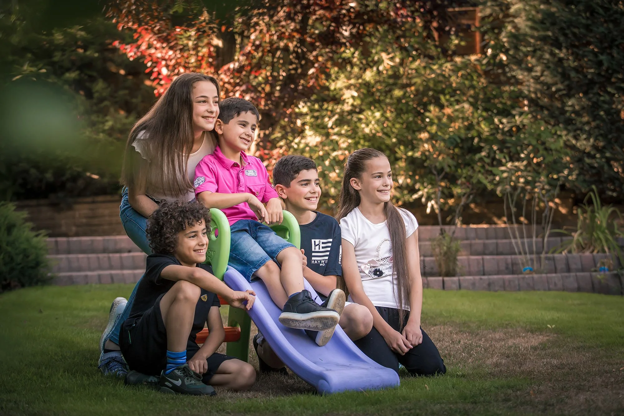 family portrait of children sitting on slide in garden in manchester