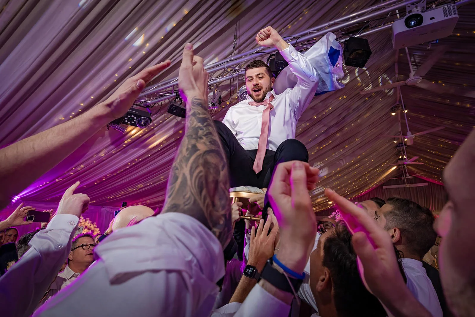 groom lifted on chair during wedding reception at heaton house farm