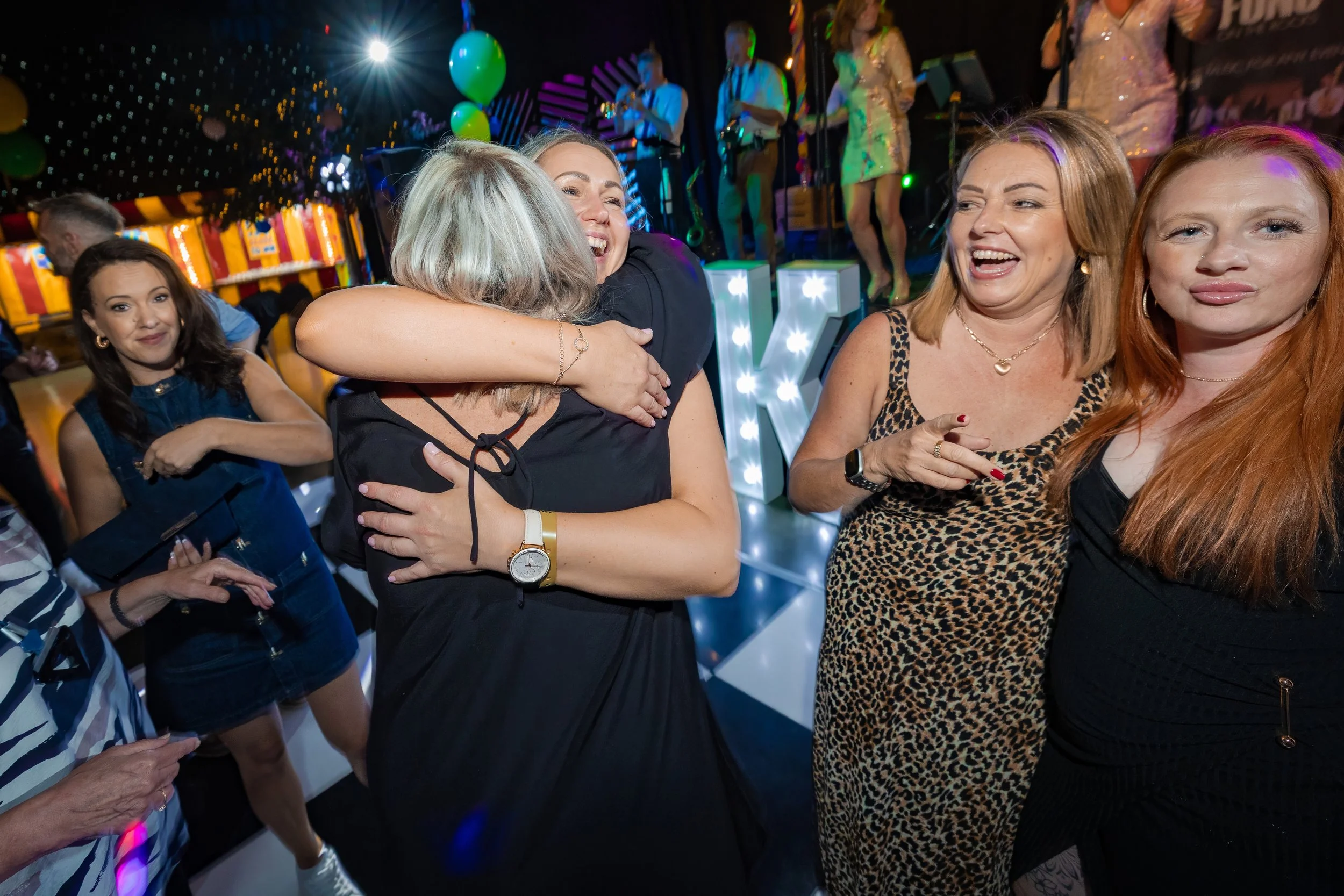 company-celebration-photography-guests-hugging-dancefloor-live-band.jpg