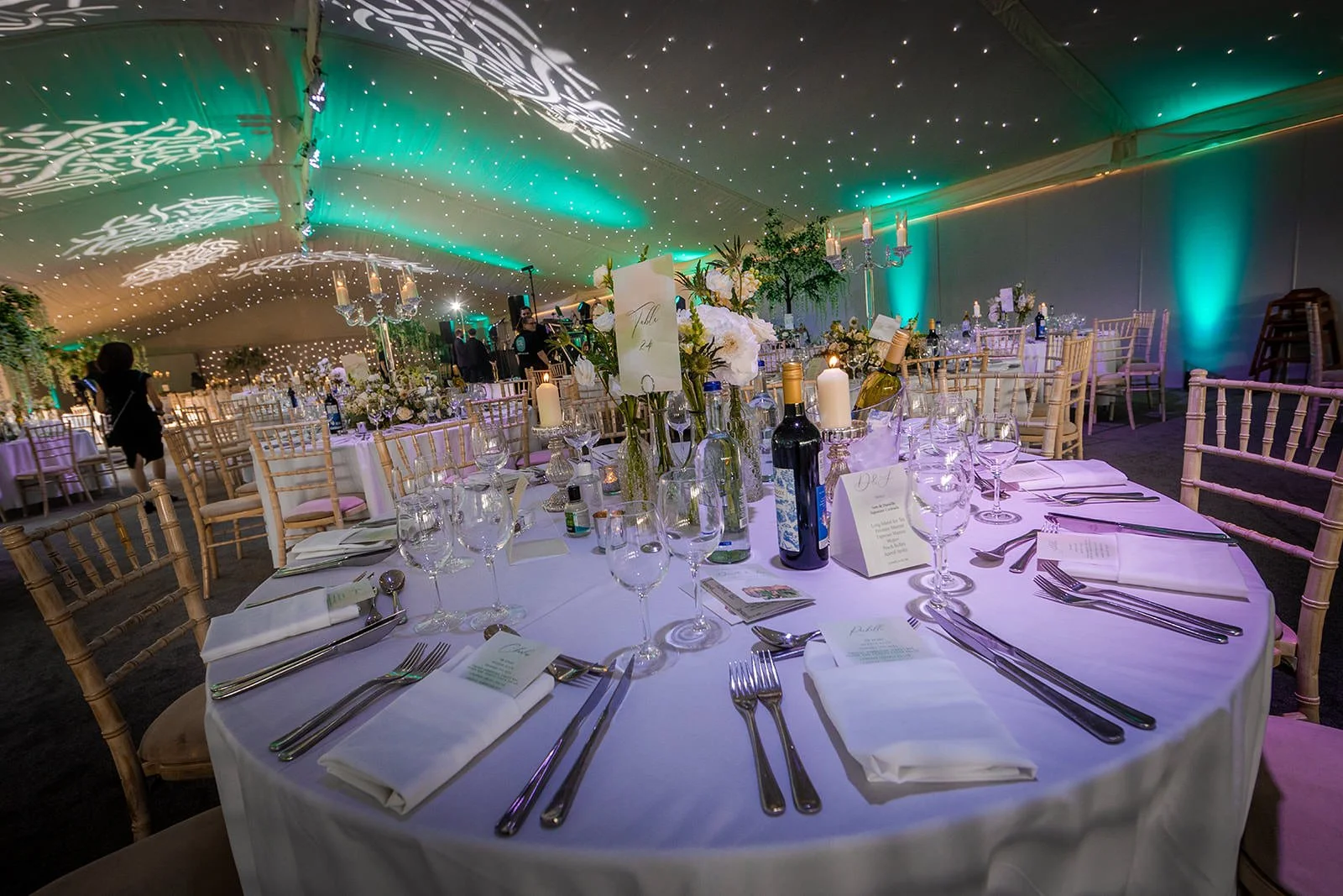 Marquee table setting with tall floral centrepieces and warm lighting, Nunsmere Hall
