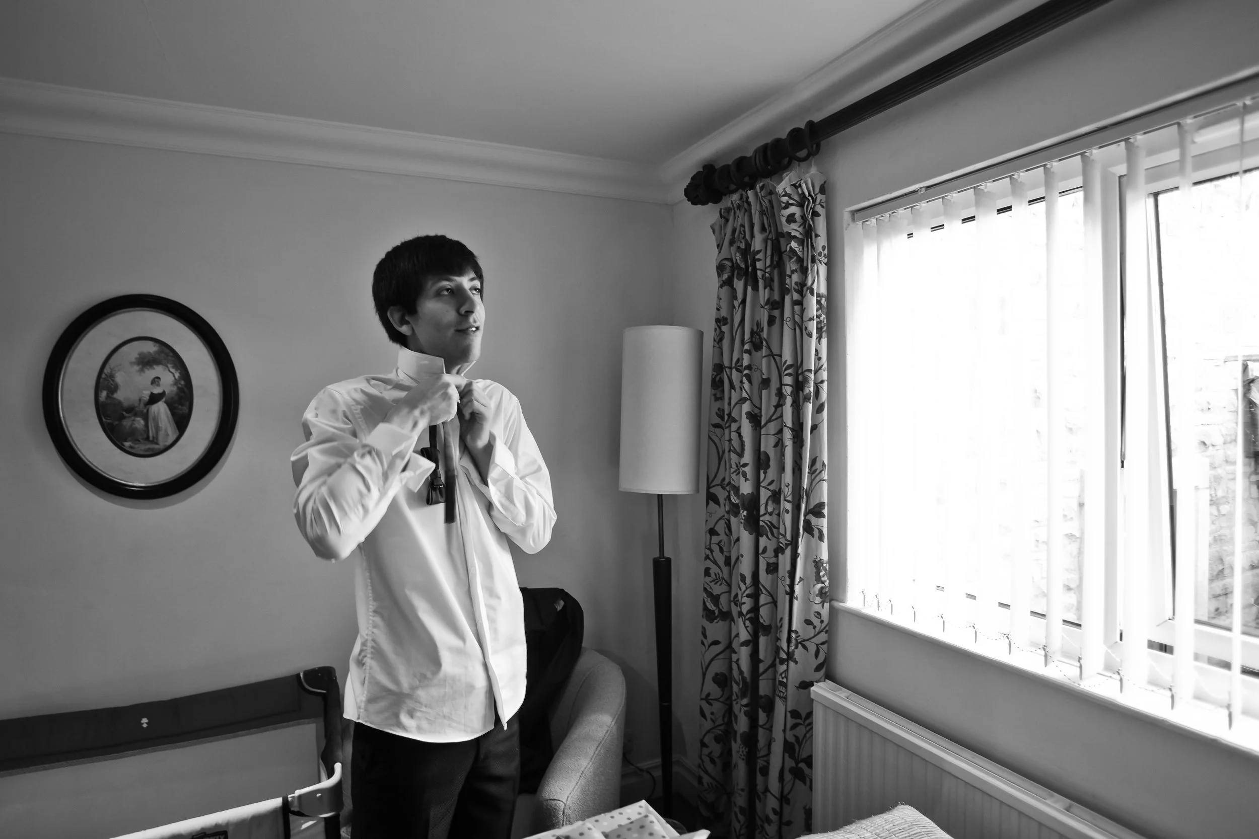 groom gets ready by window during prep at last drop wedding venue