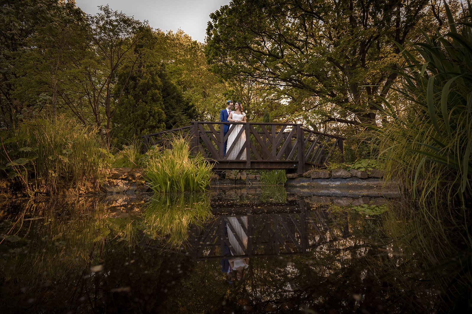 romantic newlywed bride and groom couple portraits on bridge in italian garden at nunsmere hall in cheshire