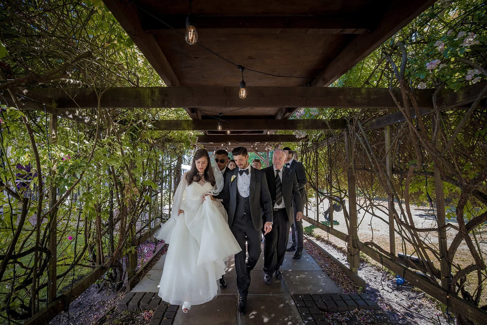 Couple walking through lit pergola with fairy lights at Nunsmere Hall
