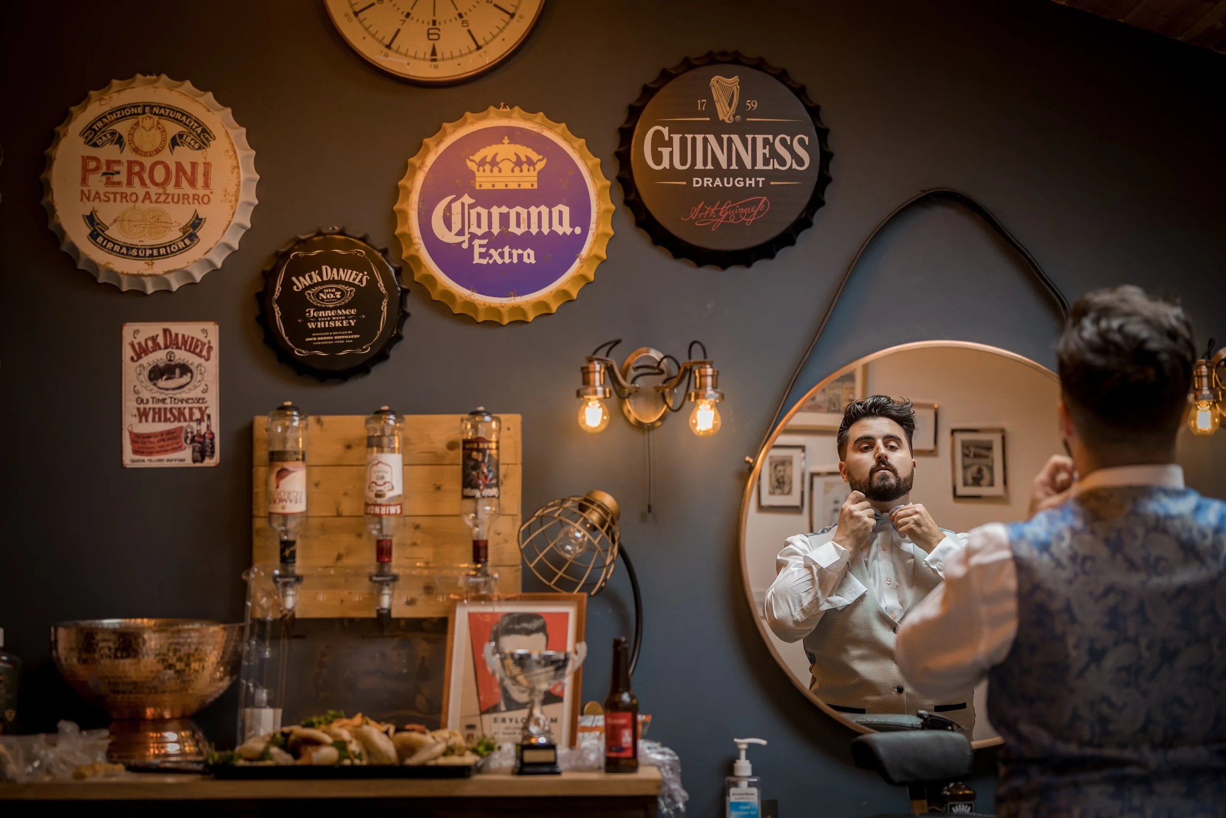 Groom adjusting bowtie in mirror during groom prep