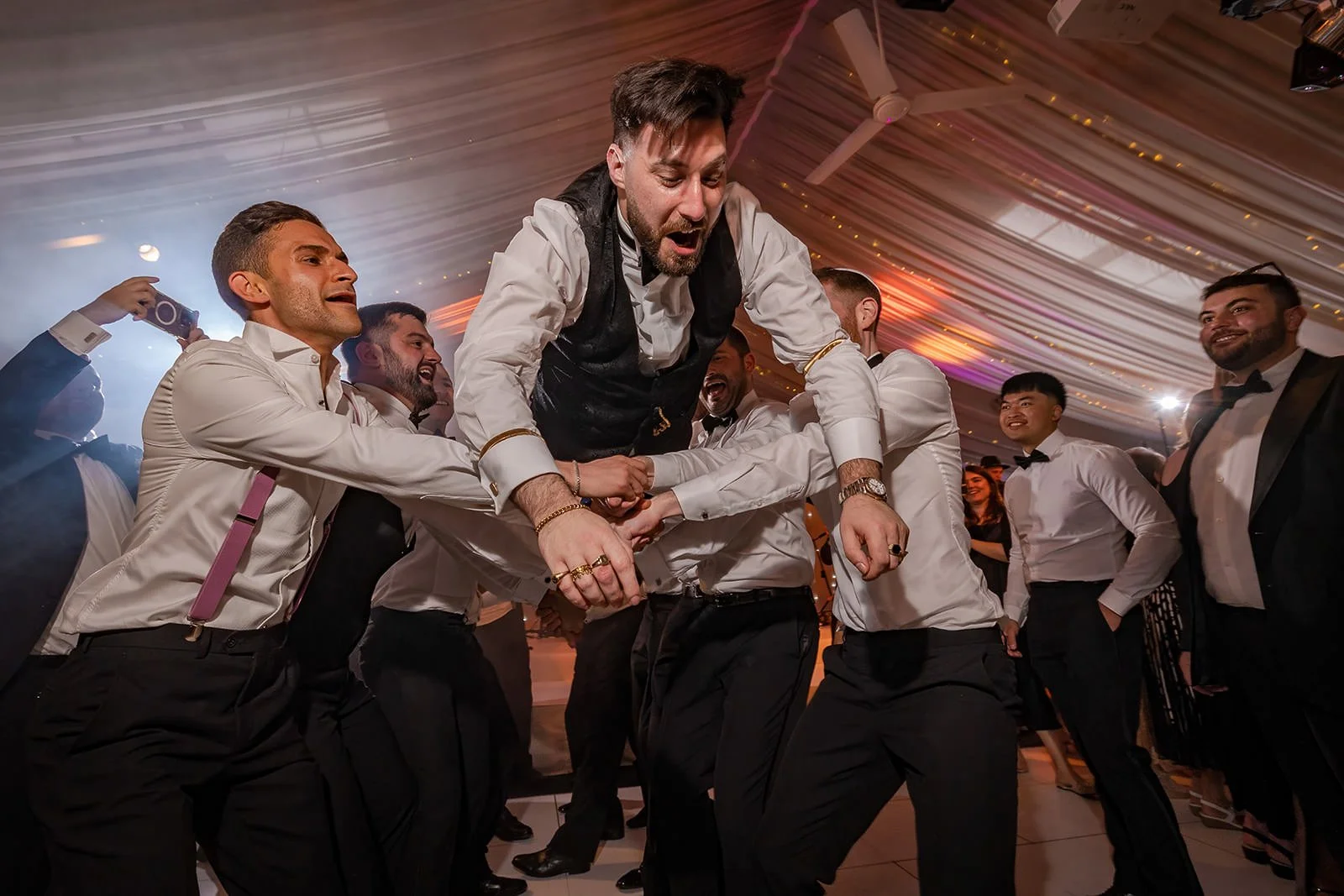 groom thrown in air on dance floor during wedding reception at heaton house farm