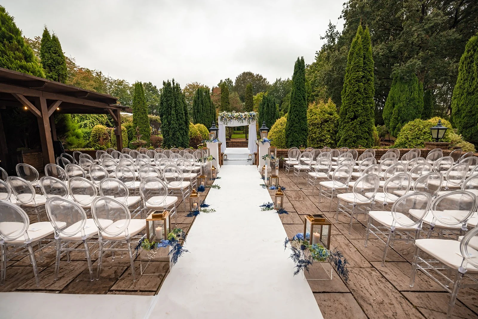 White chairs and blue floral aisle decorations for outdoor ceremony, Nunsmere Hall
