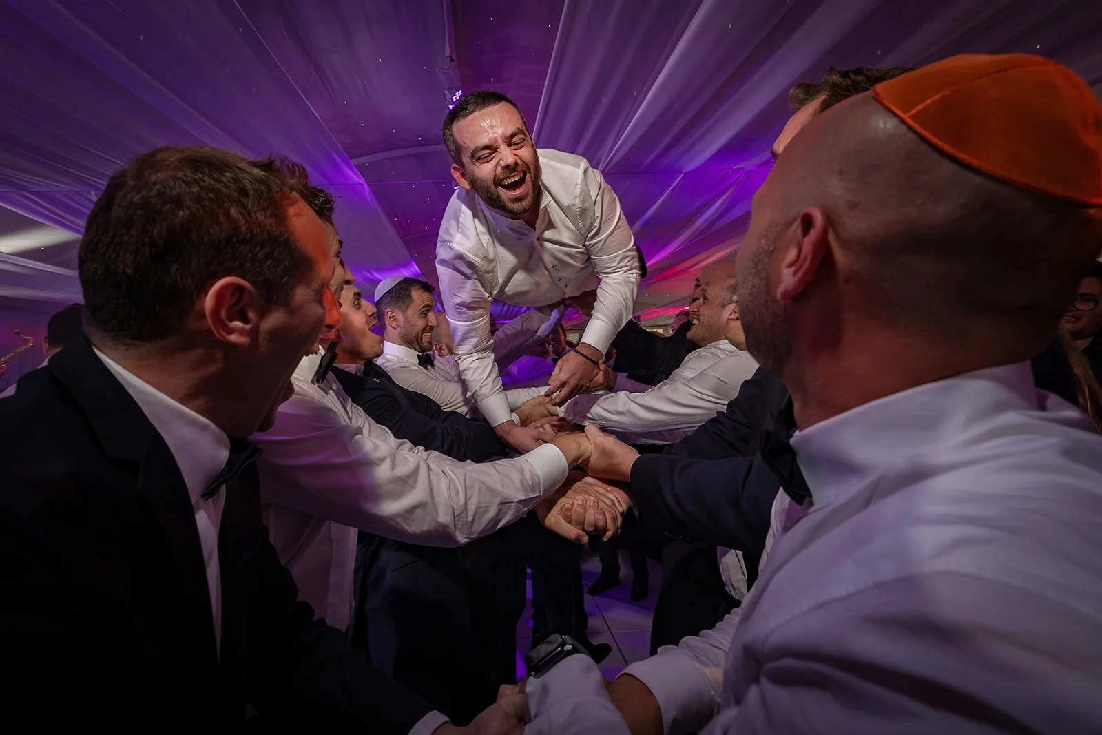 groom thrown in air during wedding evening reception at nunsmere hall venue in cheshire